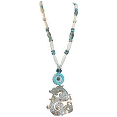 LB propose un pendentif en pierre chinoise sculptée, une broche en émail et des perles en os et turquoise