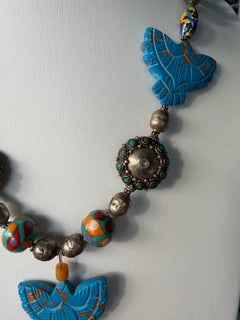 LB propose un collier en argent tibétain, verre vénitien et céramique, orné de perles sculptées en forme d'aigle
