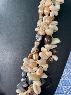 LB ofrece un collar redondo de varias vueltas con conchas de cauri, perlas de agua dulce, hueso, nácar y madera