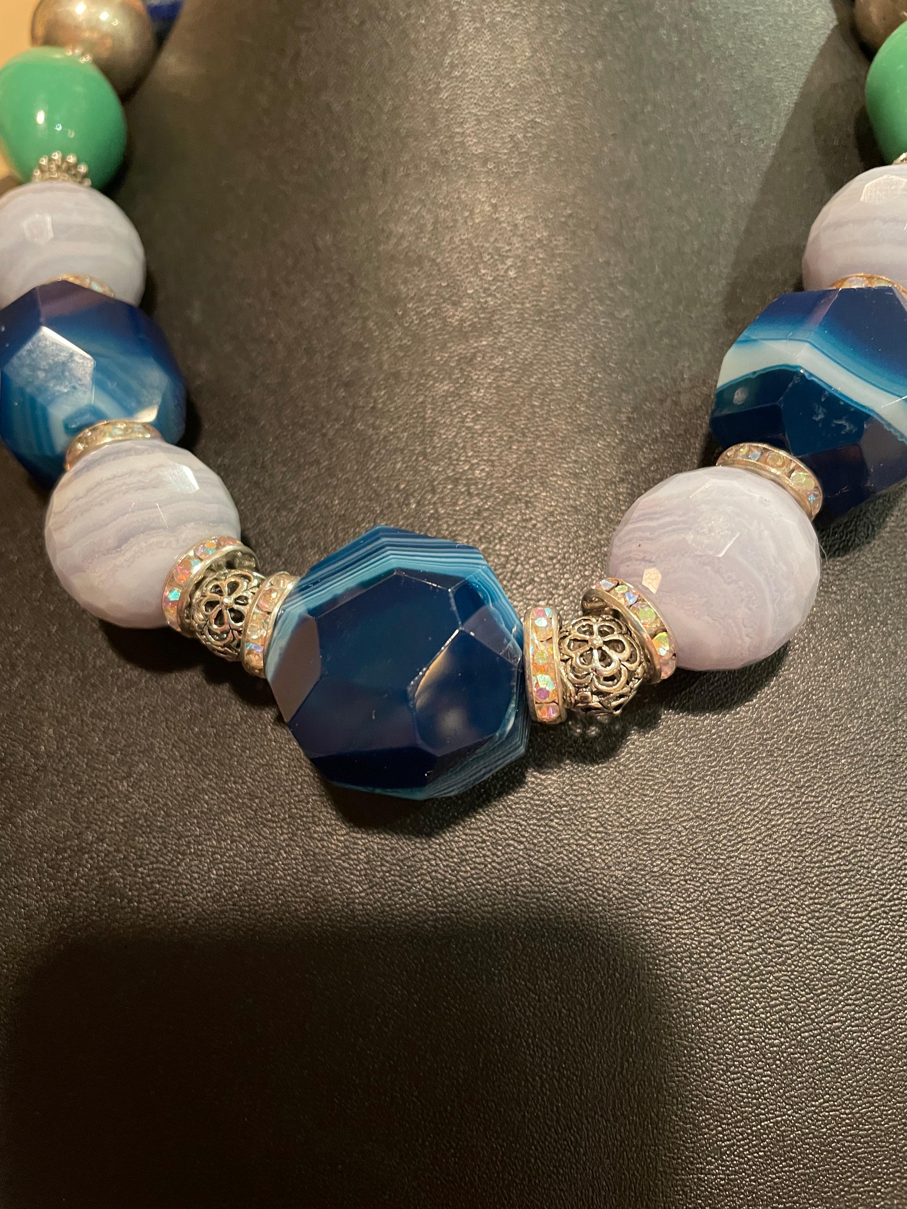 Lorraine’s Bijoux has on offer a large Blue and Blue lace Agate necklace. Large green ceramic oval beads, large Mexican Sterling Silver Rounds, Lapis Lazuli Rounds, Green Turquoise, Vintage Venetian trade beads, and crystal rondelles enhance the