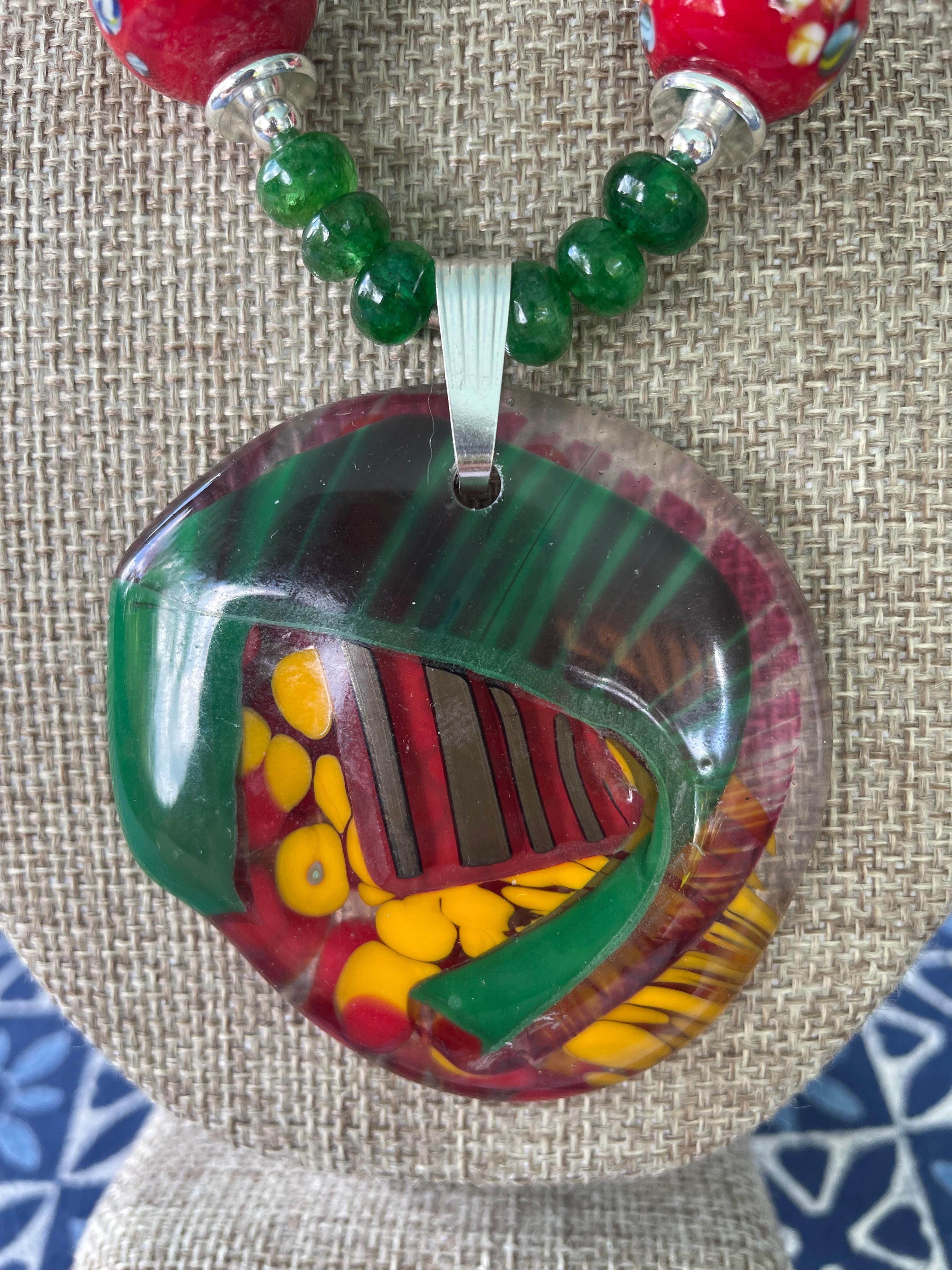 Lorraines' Bijoux propone un ciondolo in vetro libero francese multicolore (proveniente da Amboise). Questo centrotavola con rossi, verdi e gialli è impreziosito da rondelle cinesi di corallo rosso, veneziane rosse e da una serie di oggetti di