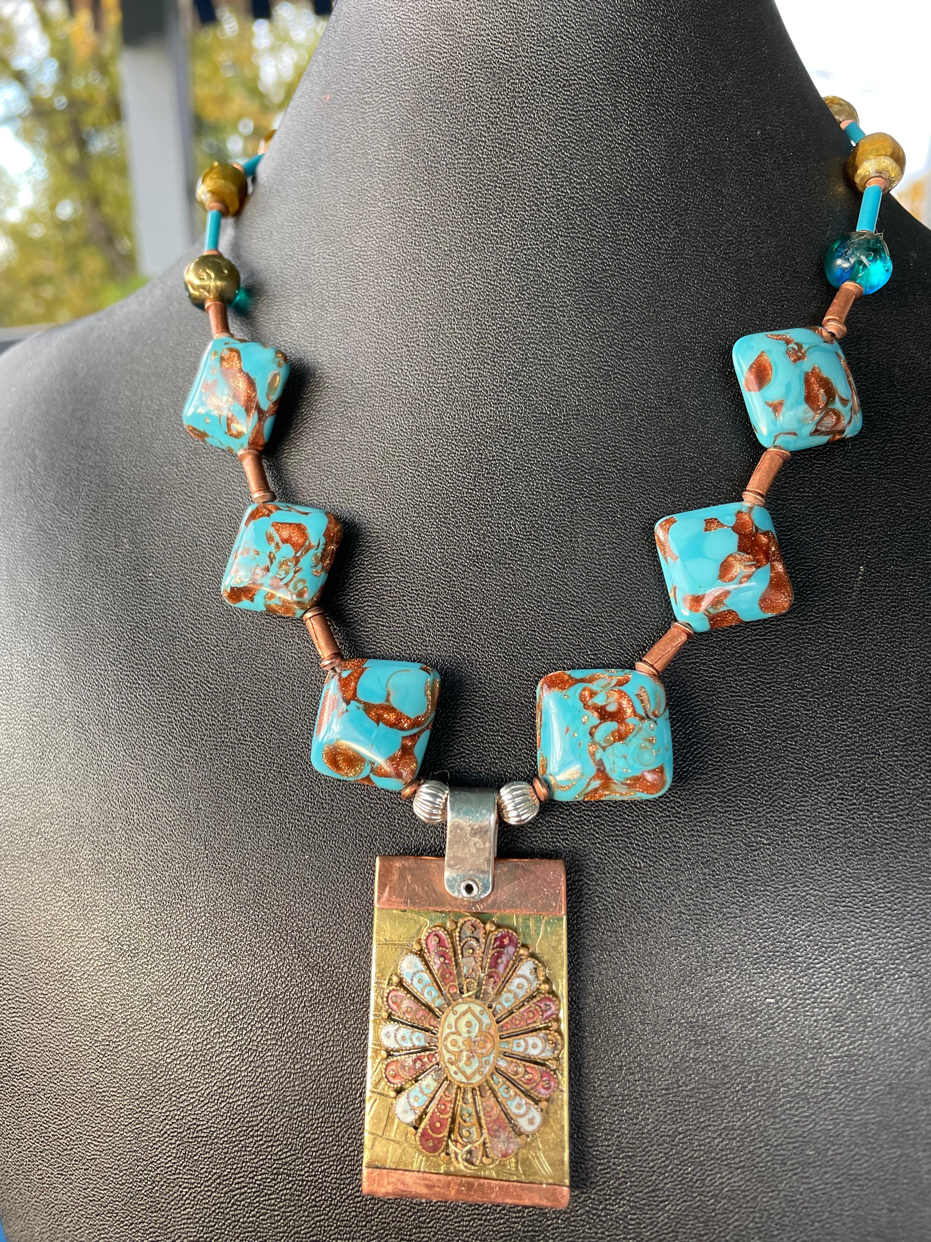 Lorraine’s Bijoux has on offer a Vintage Square Venetian glass beads necklace with a Vintage Brass, Copper, and Silver Pendant. An Antique Enamel and Brass Italian Medallion is centered on the multi metal tag and vintage glass gold beads and