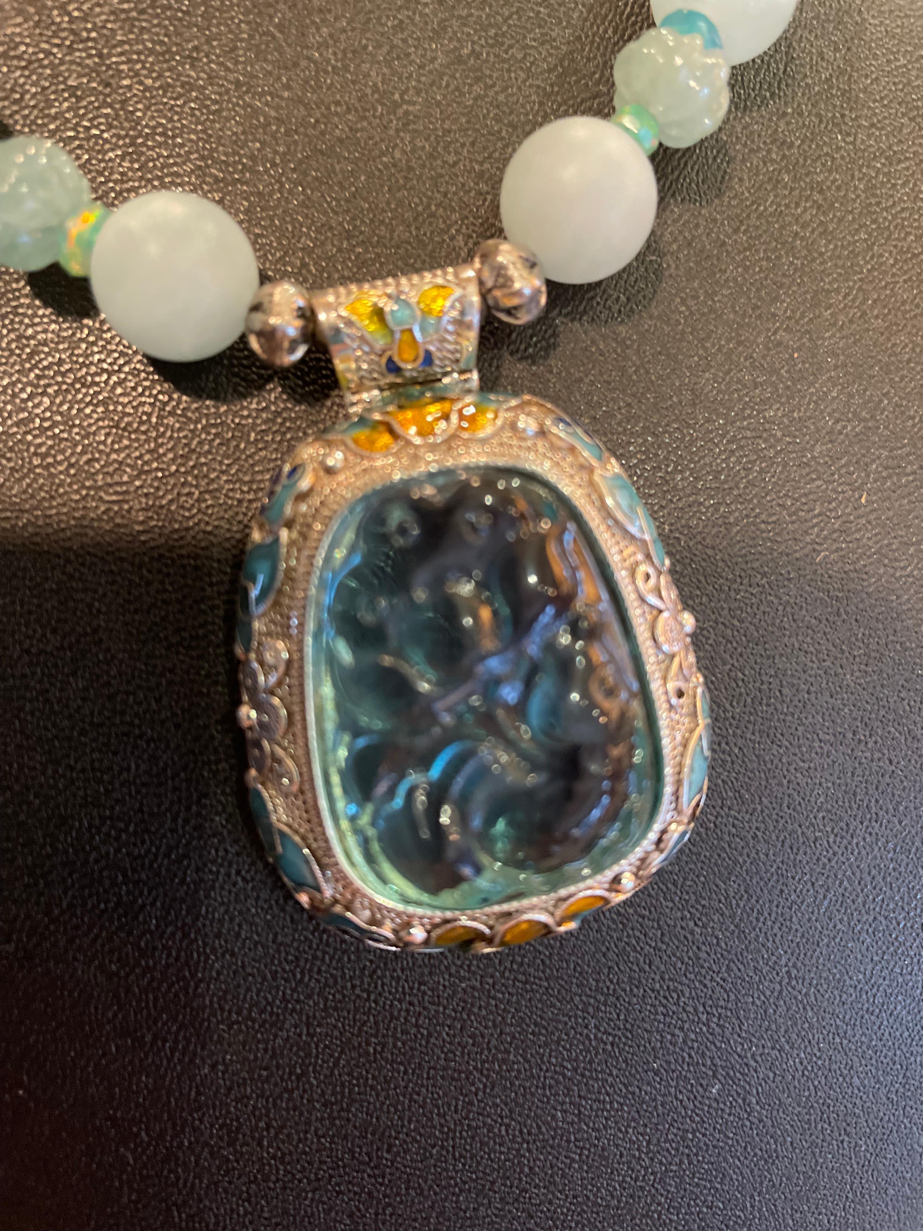 Lorraine’s Bijoux offers a new Sterling Silver ,Figural Aqua Glass and enamel lovely pendant necklace. The Aquamarine matte beads and carved Aquamarine melon shaped beads with blue opal and sterling silver spacers add richness and drama. There’s a