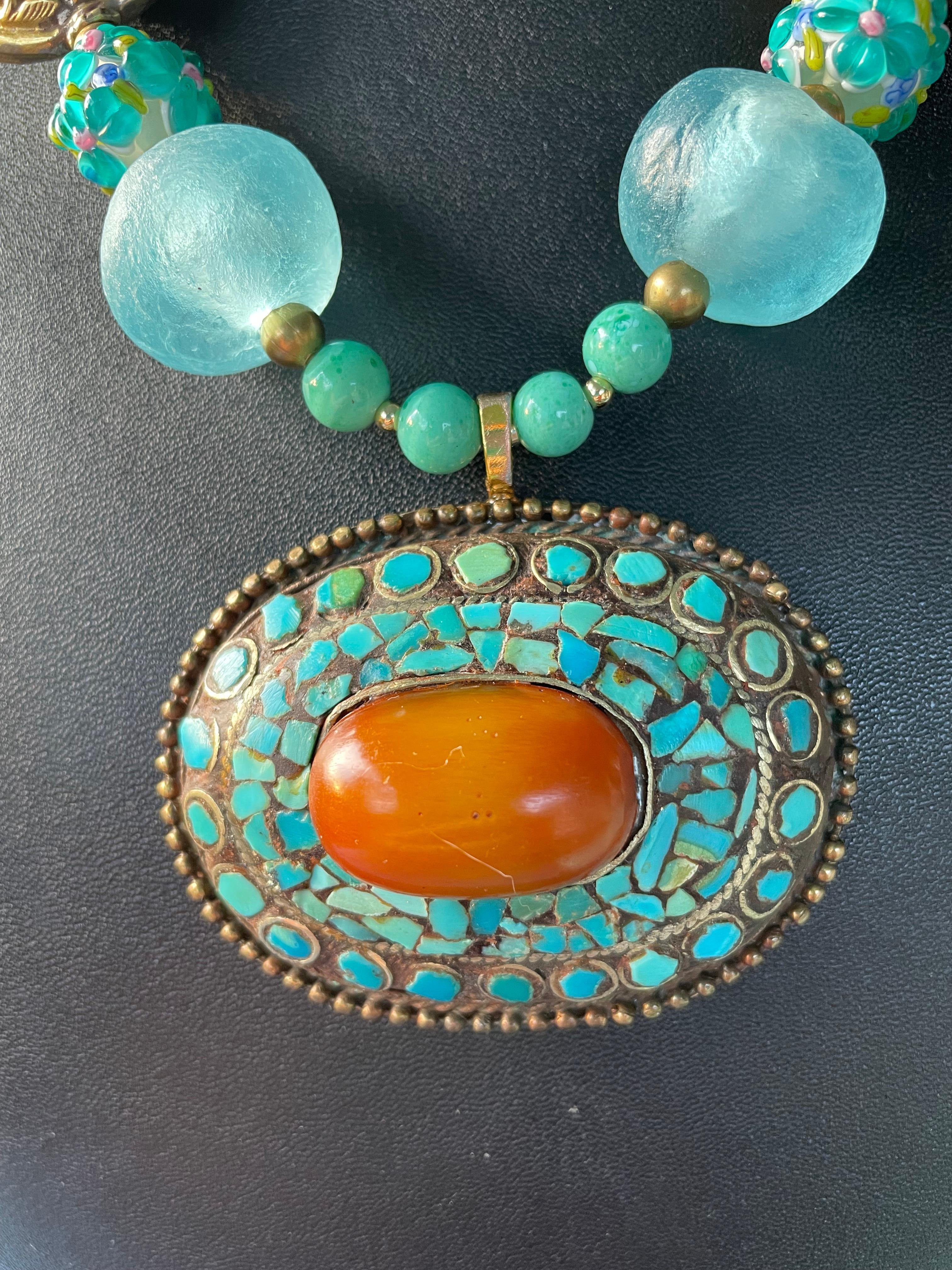 Lorraine’s Bijoux has on offer a Large Vintage Tibetan inlaid pendant necklace. Turquoise and Amber stones are artfully inlaid into a Brass framing and all is enhanced by Large beach glass rounds, handmade glass overlay ( multi shades of blue)floral