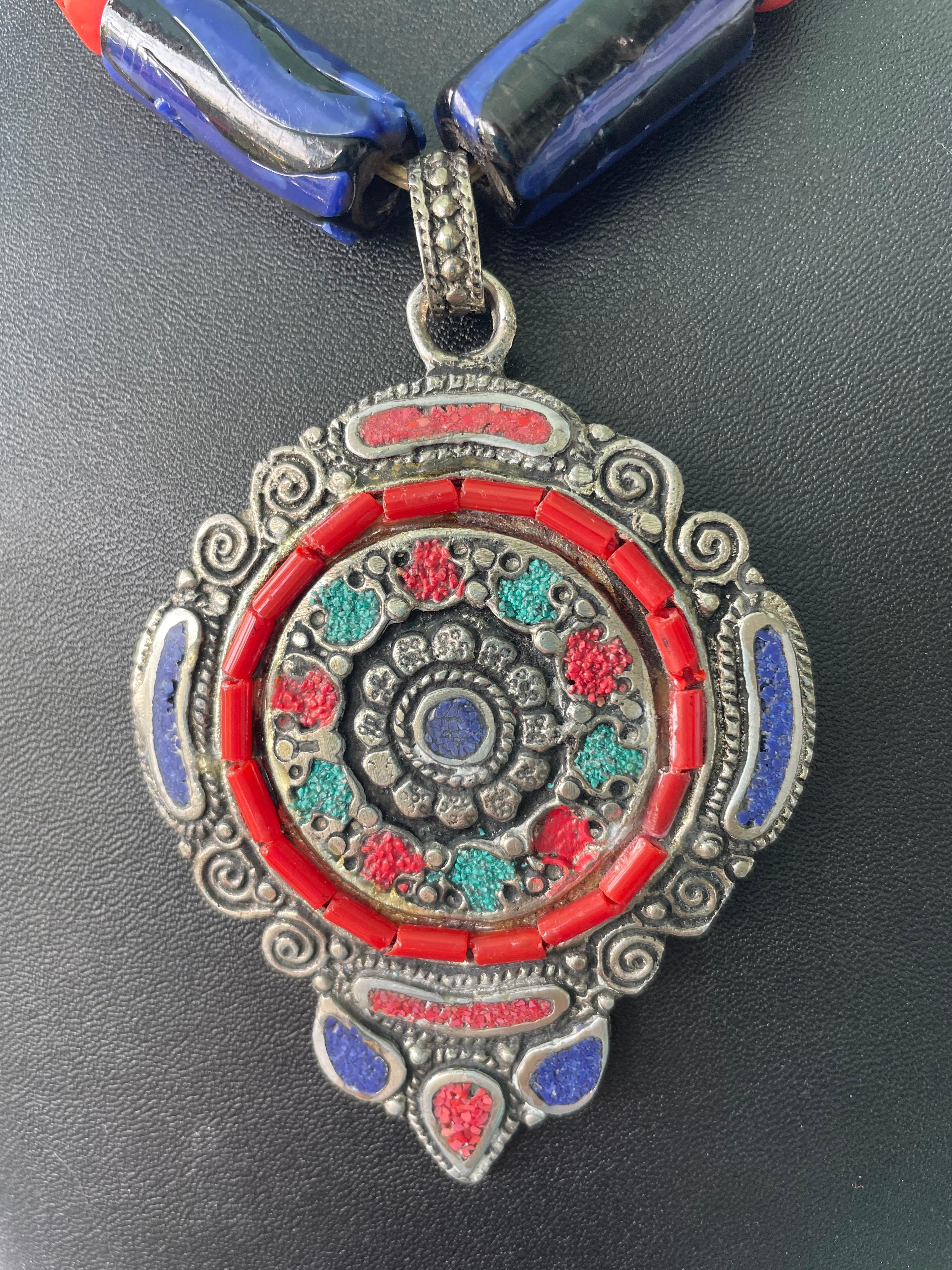 Lorraines' Bijoux propone un grande centrotavola tibetano intarsiato (con pietre semi preziose). Grandi perle di vetro veneziane africane dai colori intensi arricchiscono il ciondolo. I distanziatori in argento Sterling e le perline africane in