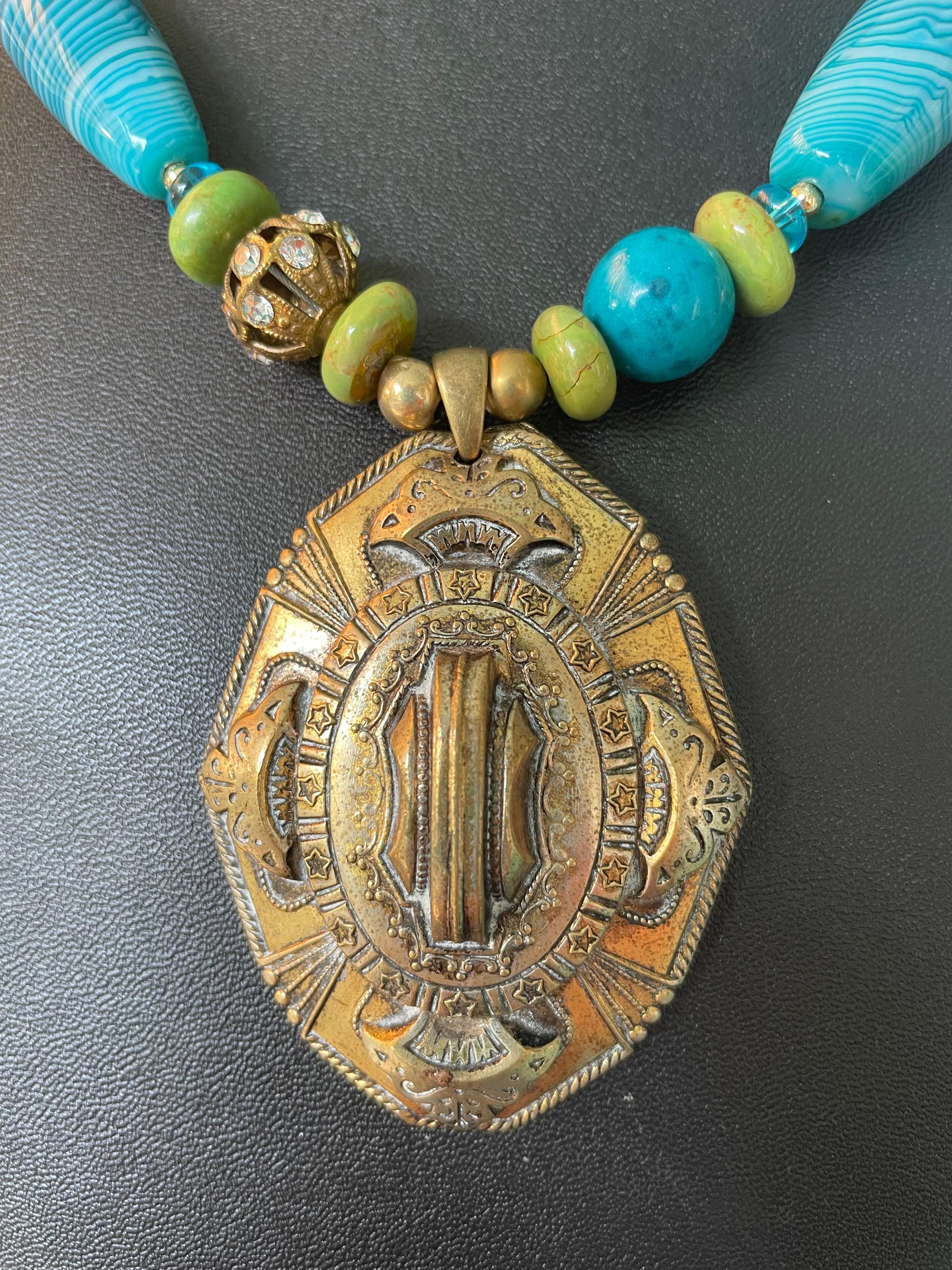 Lorraines' Bijoux offre un grande ciondolo in ottone in stile barocco della metà del XX secolo con una bella patina. Grandi agate tinte di blu, rondelle di turchese verde, perle di vetro soffiato blu e distanziatori in Vermeil arricchiscono questo