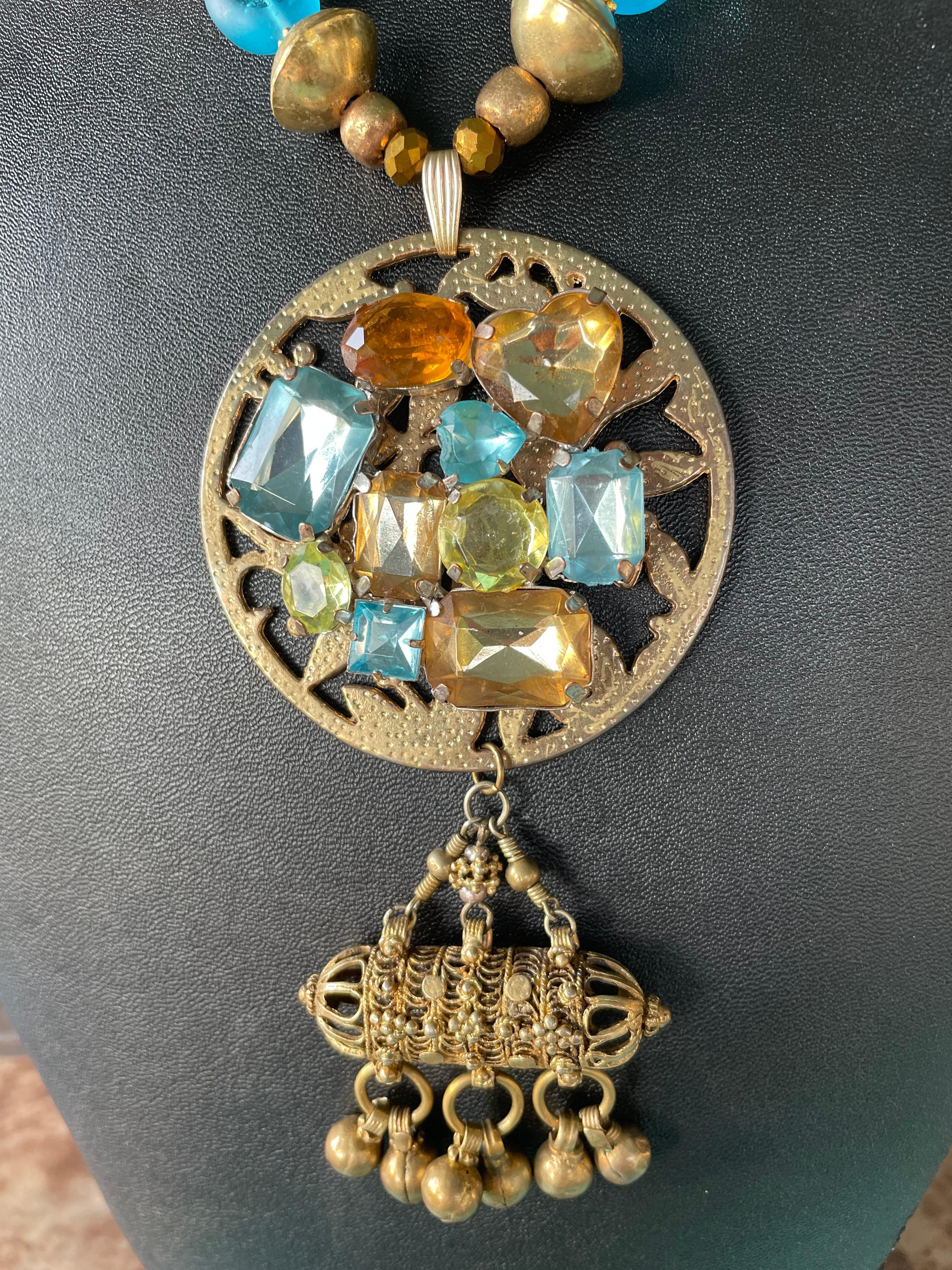 Lorraines' Bijoux propone una collana con due spille vintage anni '50 e una goccia afgana pendente in ottone. Intricate perline in vetro veneziano, perline tibetane in ottone, perline ceche in vetro blu vintage, tondi cinesi Cloisonné e una chiusura