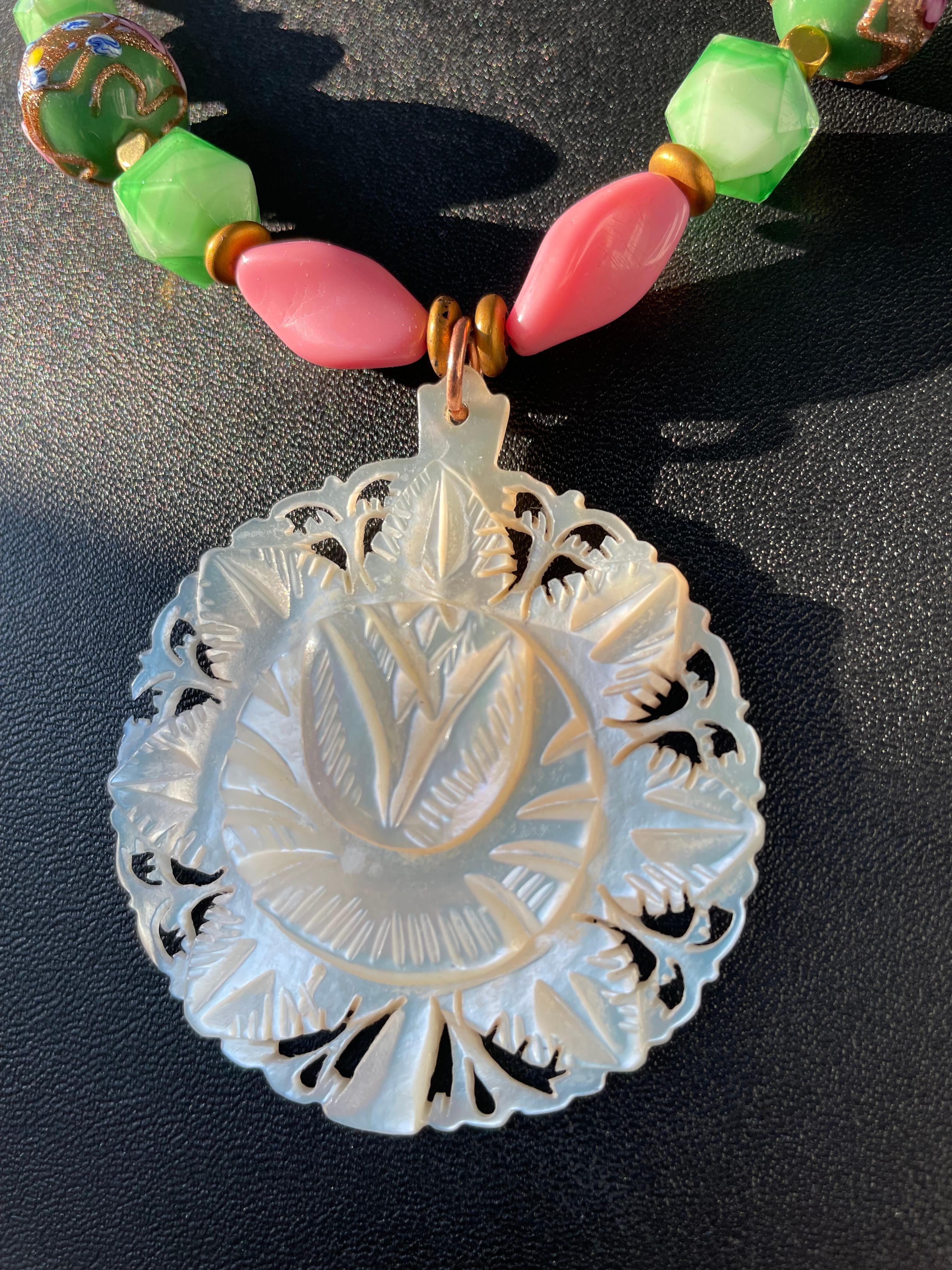 Lorraine’s Bijoux offers a vintage hand carved Indian medallion pendant necklace.
A string of all vintage Czech and Venetian glass beads add lovely pink and green colors to enhance the pendant. 
This is an extraordinarily lovely, feminine accessory