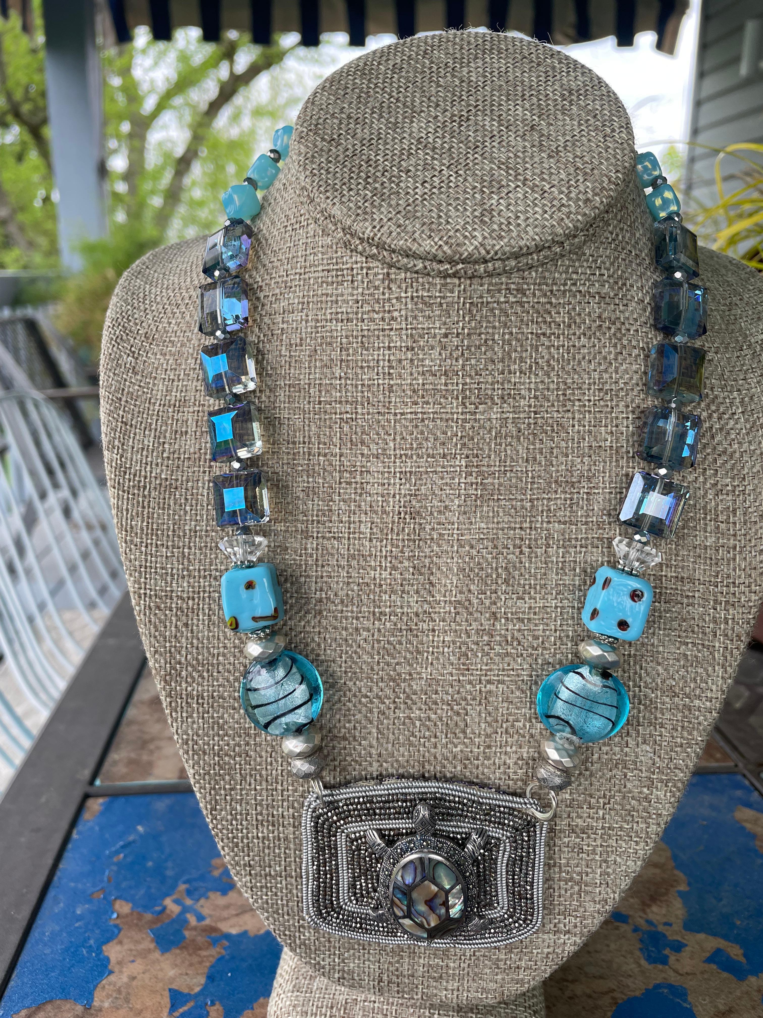 Lorraine’s Bijoux has on offer a Vintage beaded French Buckle centerpiece with a vintage Sterling Silver,Marcasite, and Paua shell turtle brooch. The string of Venetian beads, vintage square glass beads, faceted square blue crystals, faceted pyrite,