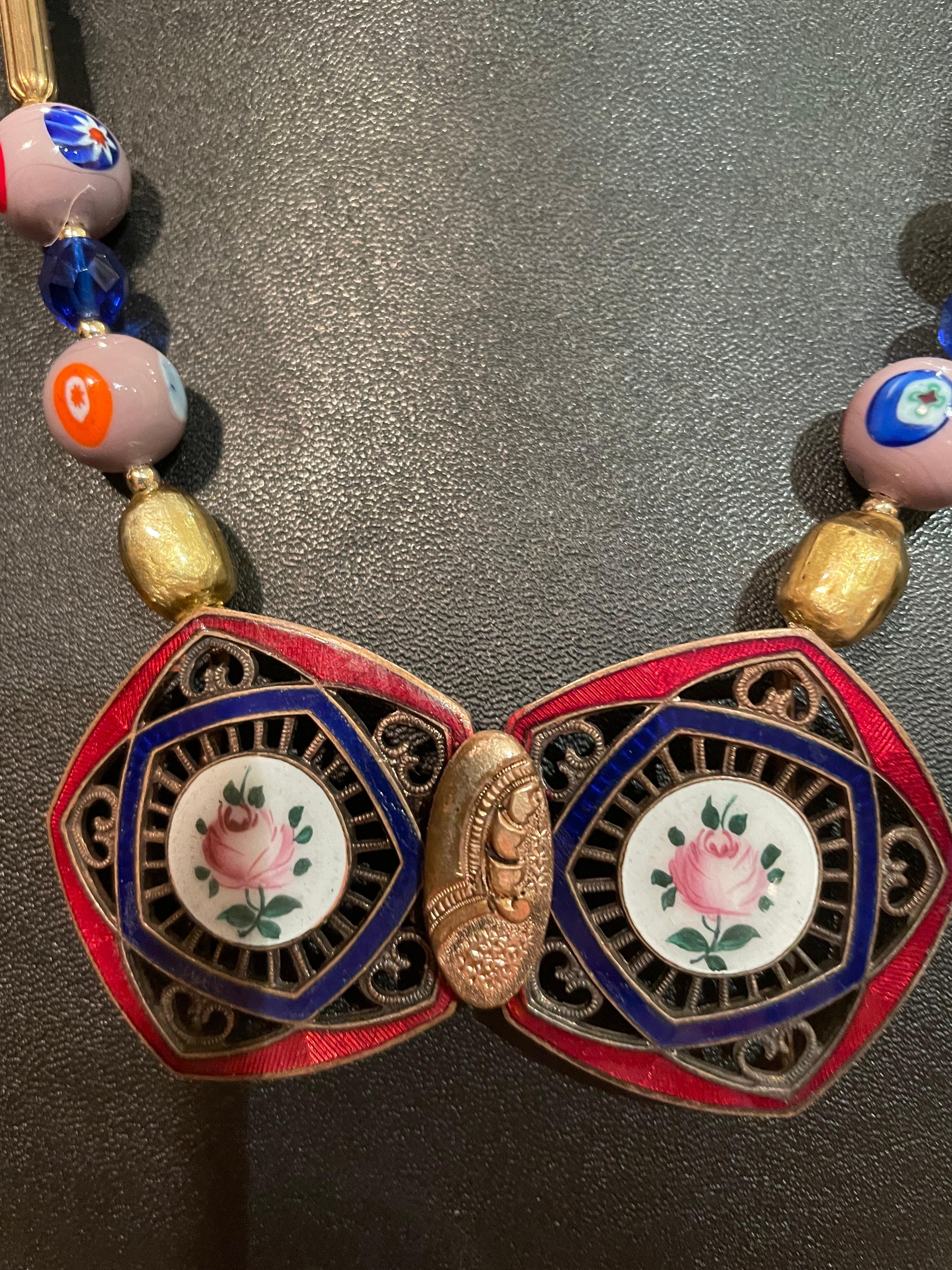 Lorraine’s Bijoux has on offer a Vintage French Enamel Blue and Red Brass Buckle
Necklace. A string of Vintage Venetian glass Mille Fiore beads, Vintage Cobalt Blue Venetian Wedding Cake handmade glass beads, vintage Czech glass metallic beads, Blue