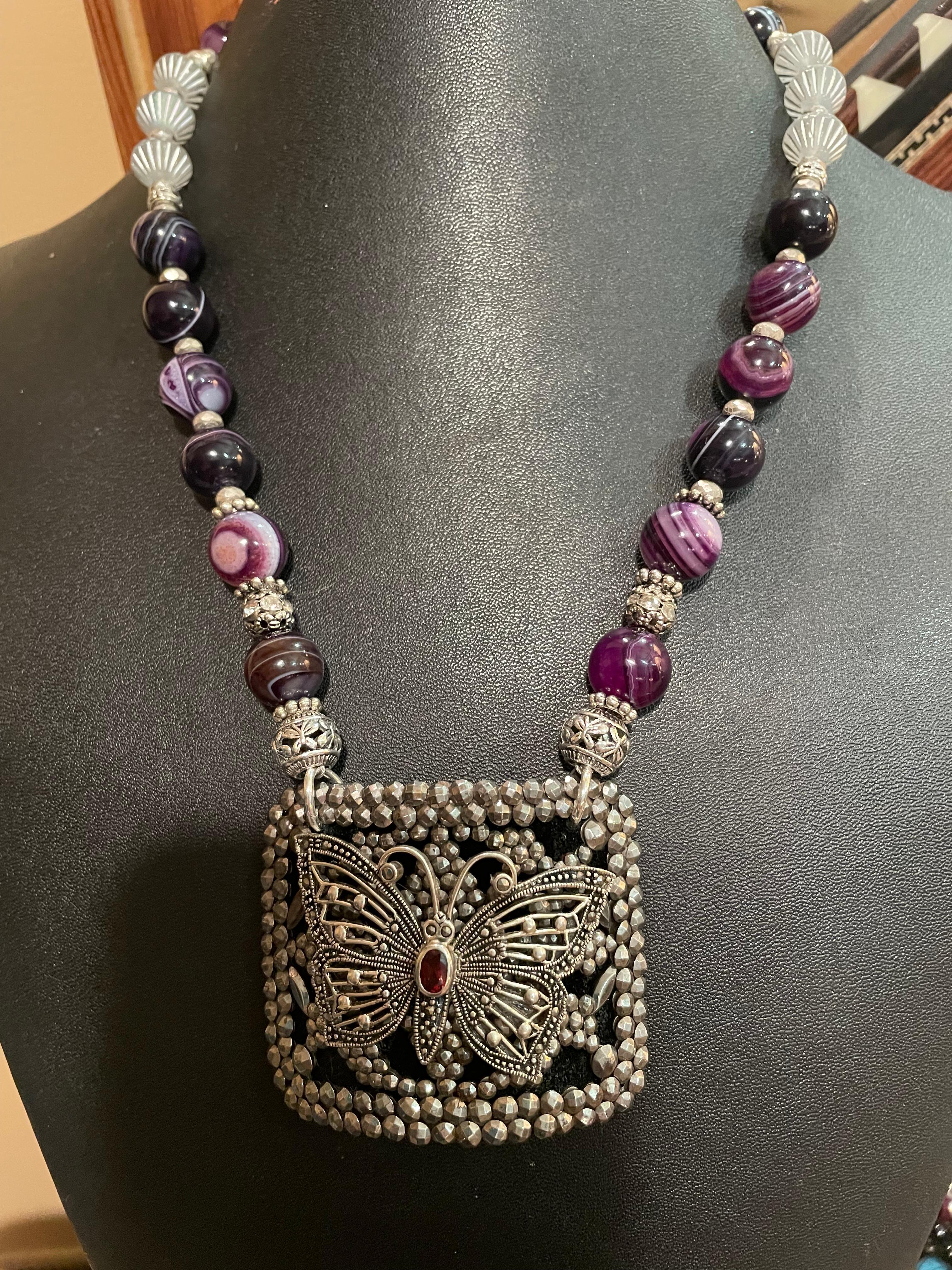  Lorraine’s Bijoux has on offer a Vintage French Steel Buckle with a Vintage Sterling Silver and Marcasite Butterfly centerpiece.
Black leather backs the buckle and sterling silver rings hold the two strings of beads. 
Amethyst and Sterling Silver