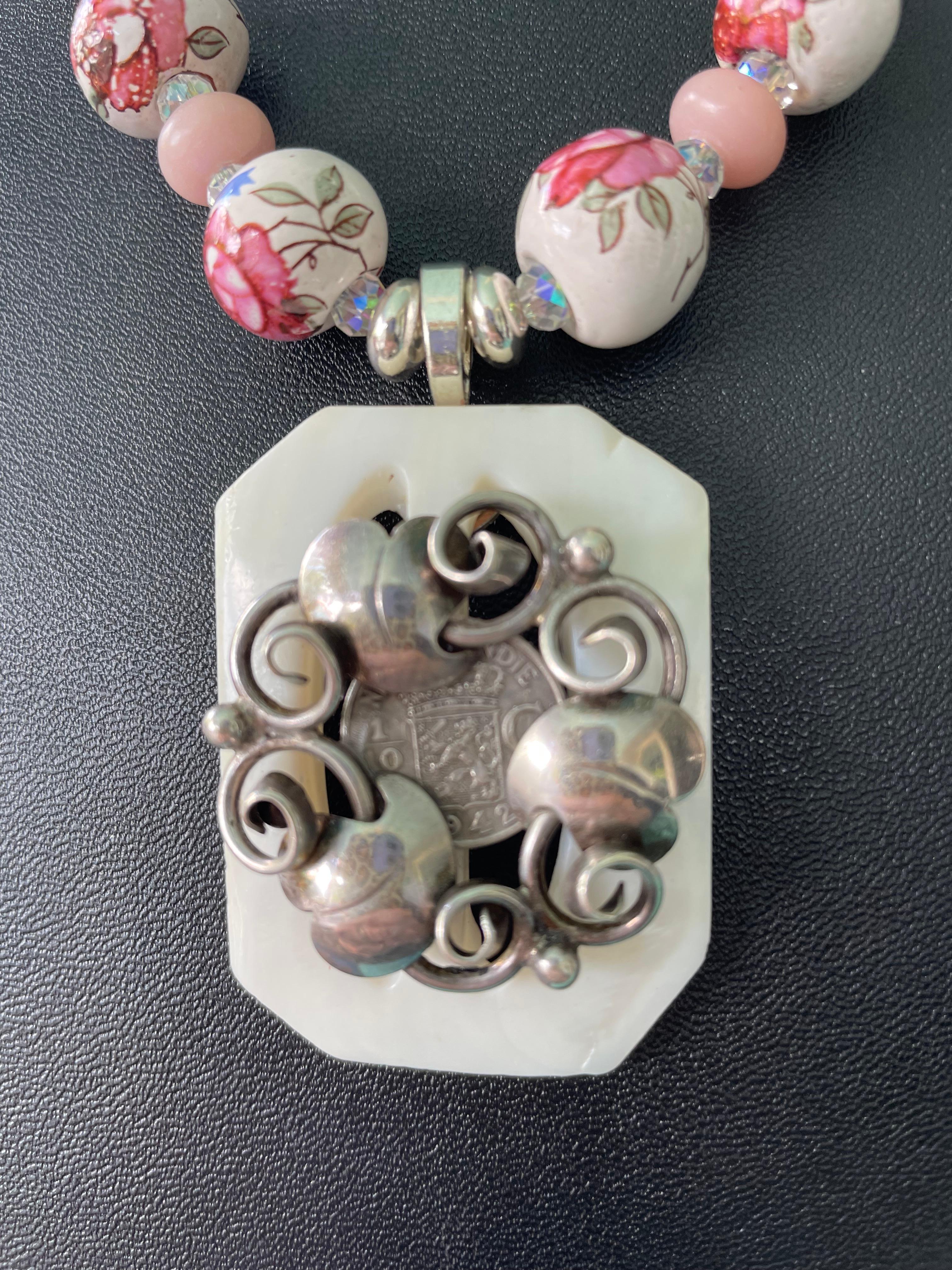 Lorraine's Bijoux bietet eine kreisförmige Blumenbrosche aus Vintage-Sterling-Silber, eine Vintage-Silbermünze auf einer weißen Perlmuttschließe an, die das Herzstück dieser hübschen, einzigartigen Halskette bildet. Gedrehte tschechische Glasperlen