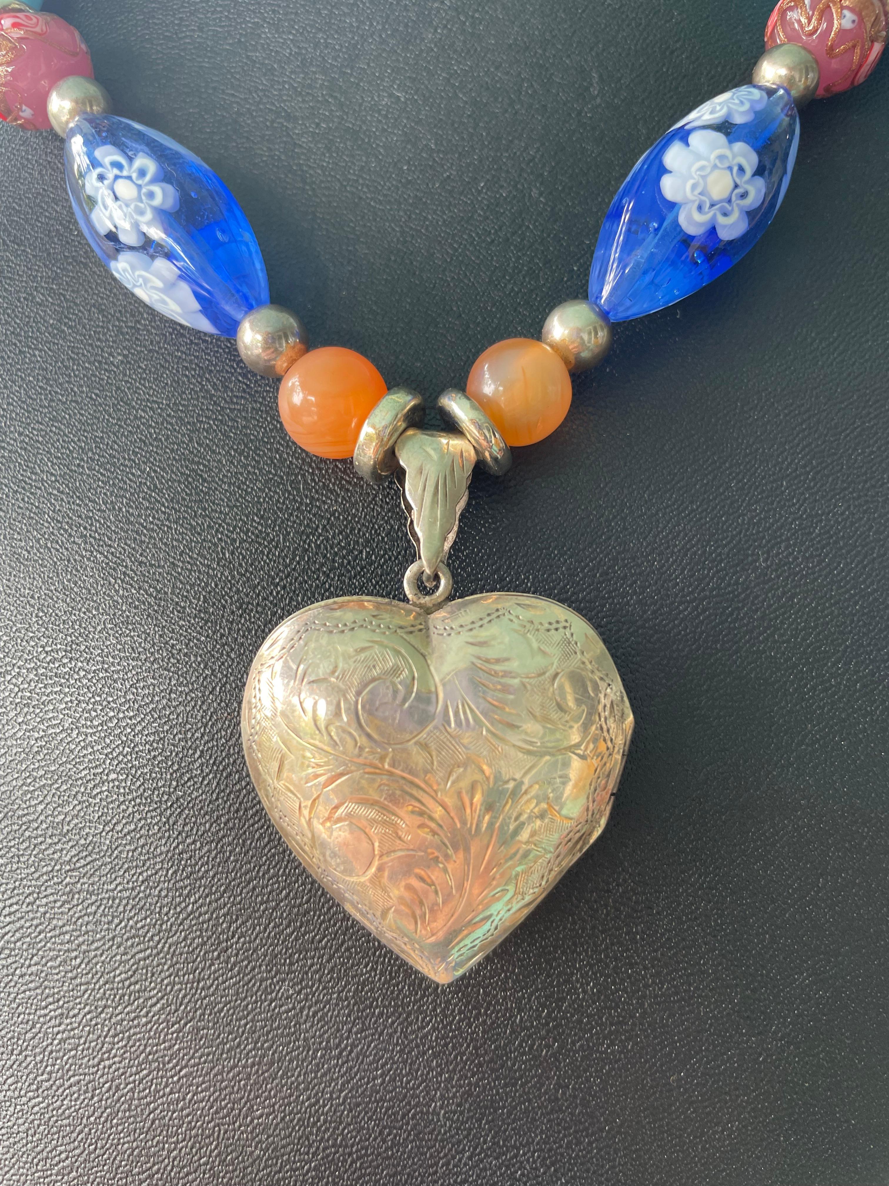 Lorraine's Bijoux bietet eine geätzte Halskette mit Anhänger aus Sterlingsilber im Vintage-Look an. Orangefarbene Karneolperlen und venezianische Vintage Mille Fiore Ovale, blaue herzförmige Murano-Glasperlen und Opalglasperlen vervollständigen