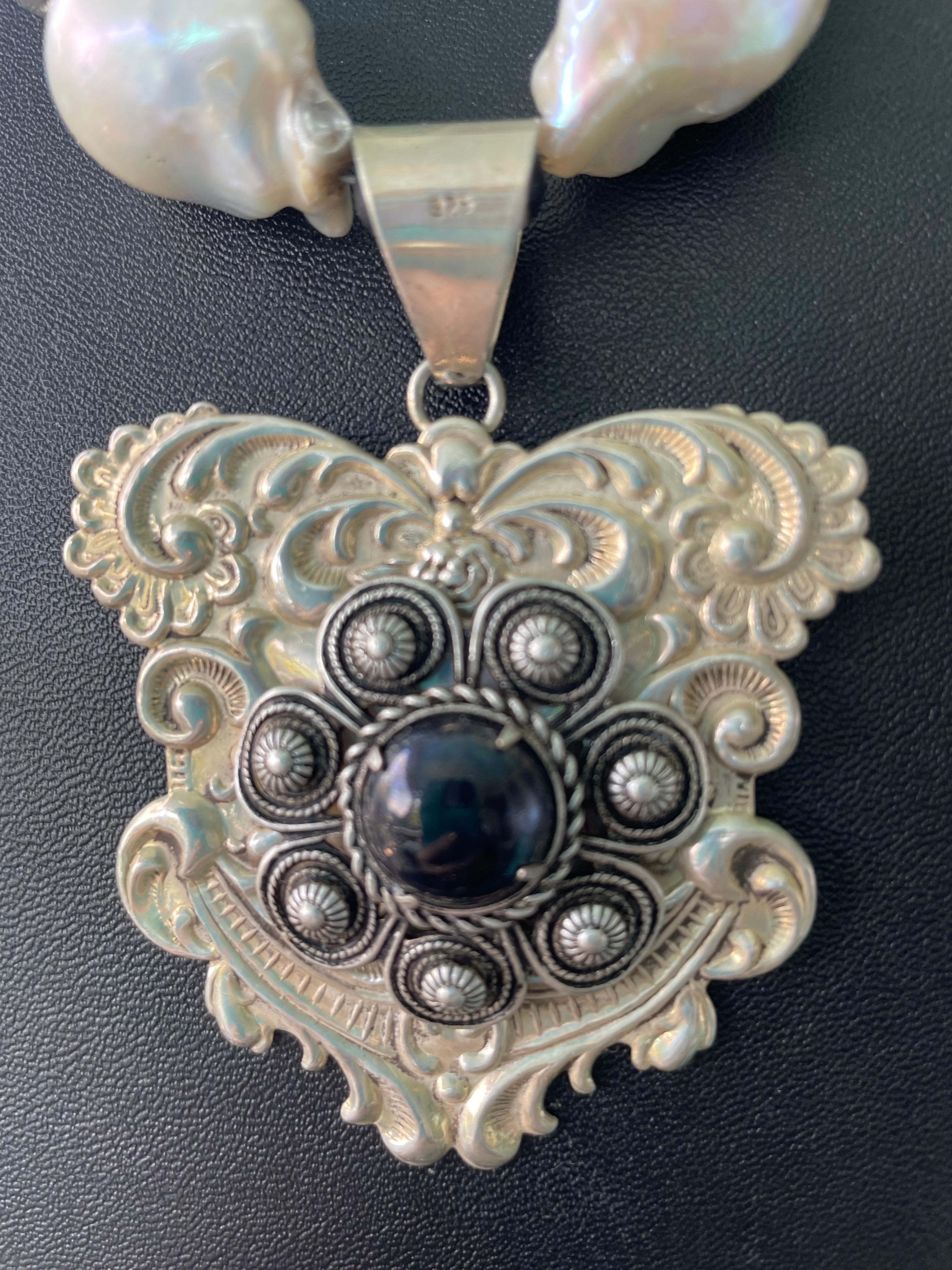 Lorraine’s Bijoux has on offer a necklace with Two vintage Sterling Silver brooches as the centerpiece. Large White and Peacock Baroque freshwater pearls, Venetian glass two tone beads, Mexican Silver Beads, Vintage Mother of Pearl rounds, African
