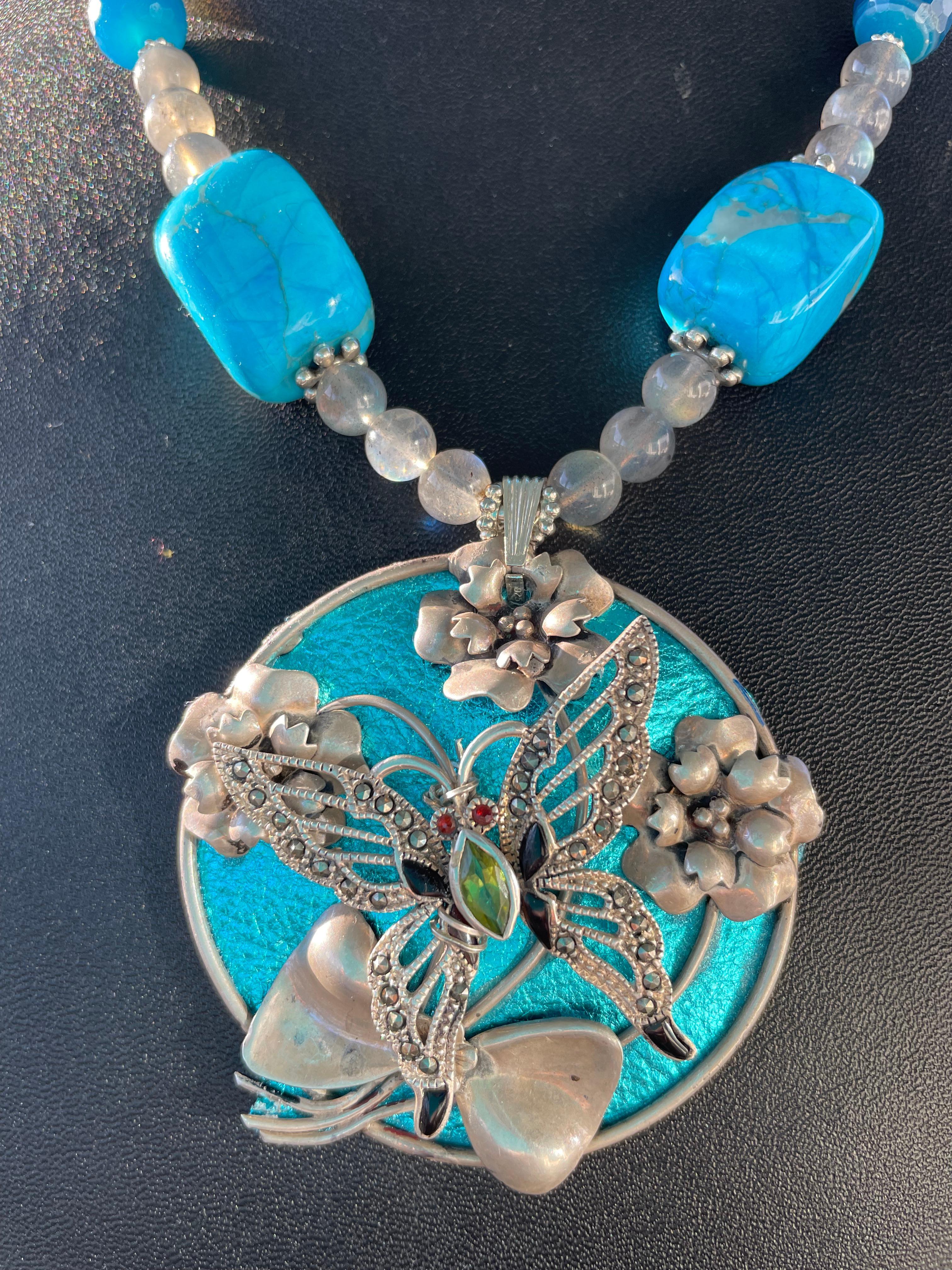 Lorraine’s Bijoux offers a Stunning and Unique pendant necklace consisting of two vintage Sterling Silver brooches ( one round floral and one marcasite inlaid ) with a background of metallic Tuquoise yummy leather. This piece is Fabulous and is a
