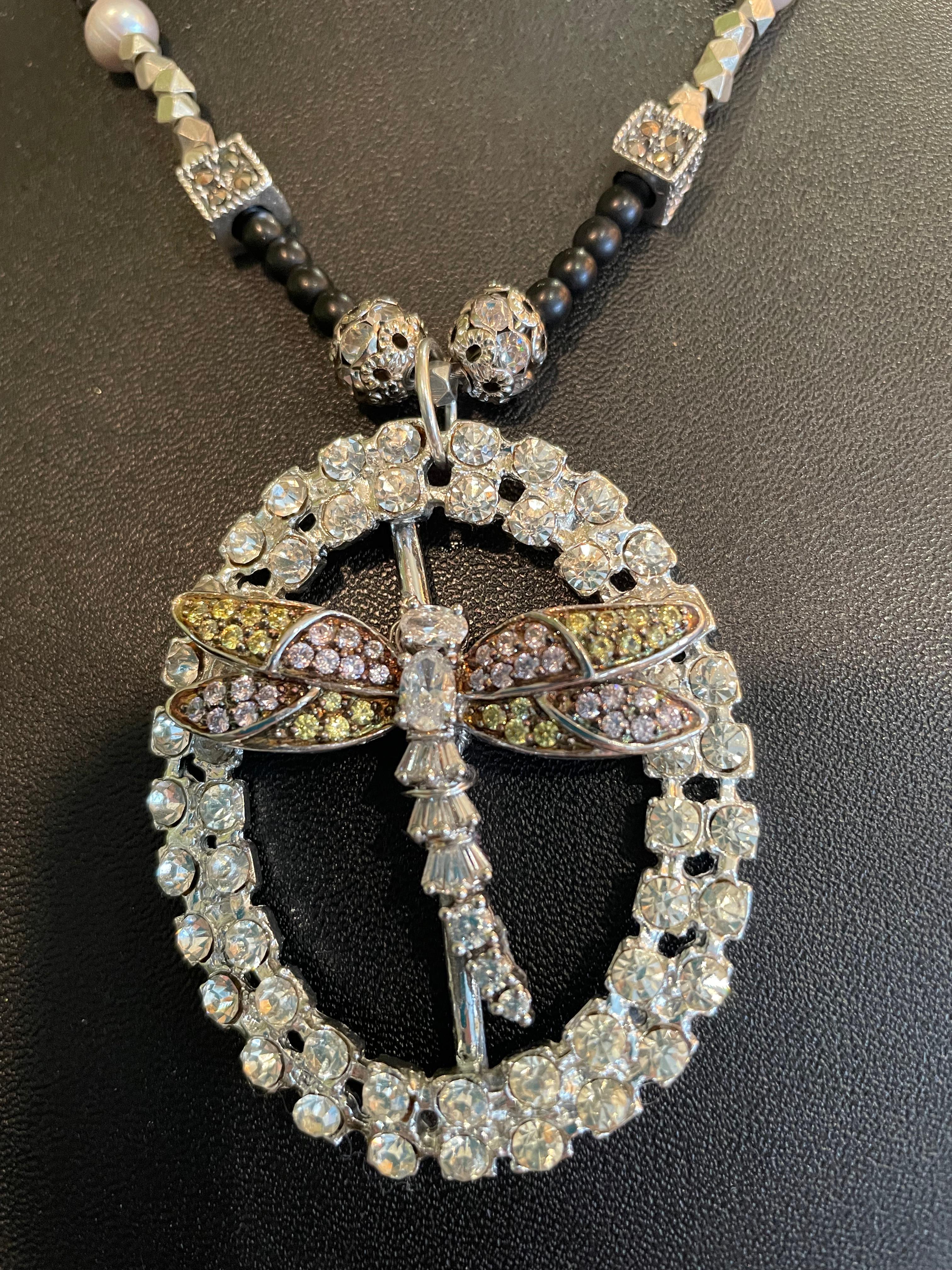 Lorraine’s Bijoux has on offer a one of a kind necklace with a Vintage Sterling Silver and crystal Dragonfly on an antique oval crystal buckle centerpiece. The addition of matte black onyx beads, crystal and silver balls, square Sterling silver and