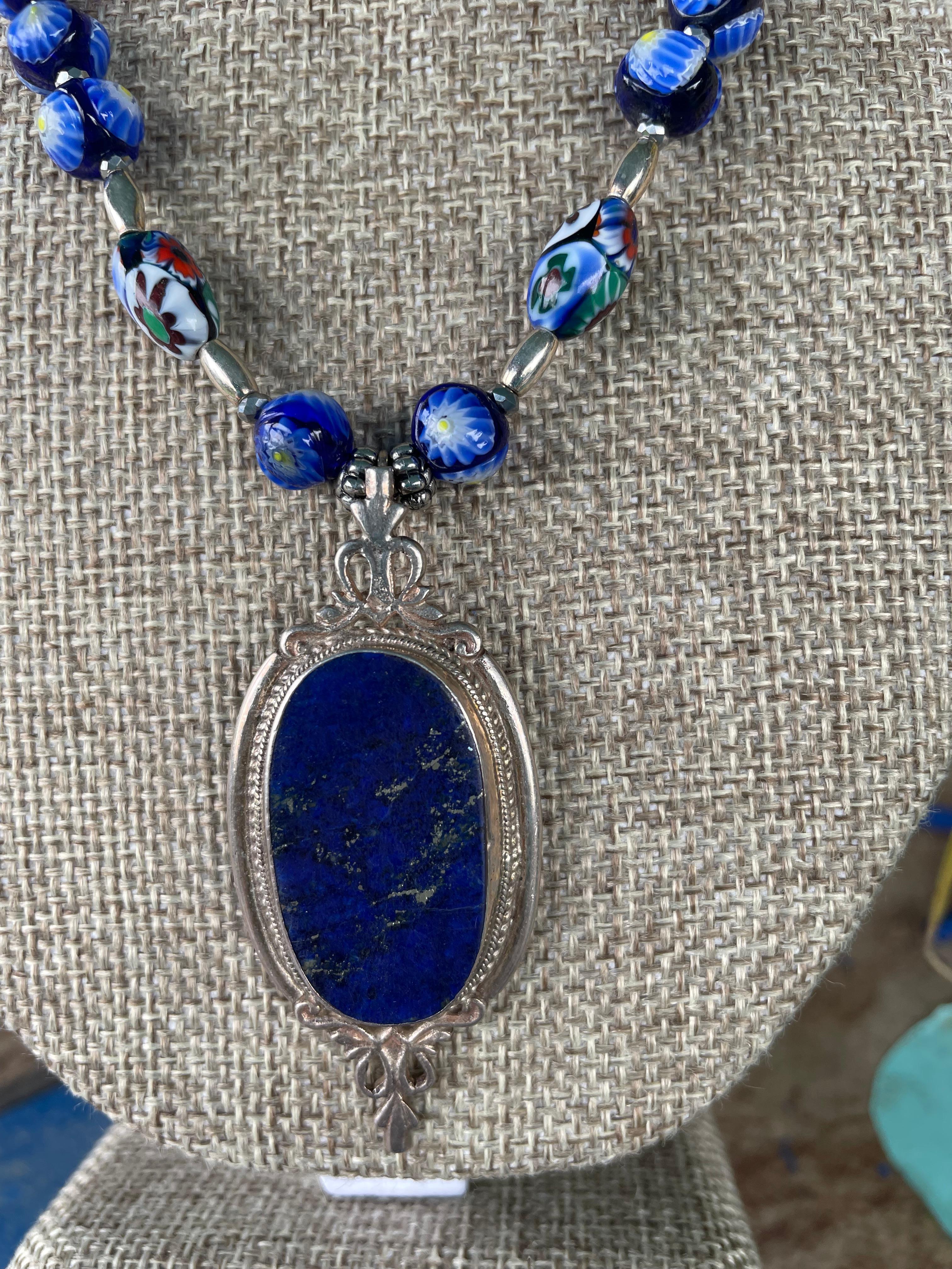 Lorraine’s Bijoux has on offer a vintage Afghani Lapis Lazuli and Sterling Silver brooch pendant necklace. A string of vintage blue Mille Fiore Venetian glass beads and sterling silver beads enhance this stunning centerpiece.A fabulous piece with