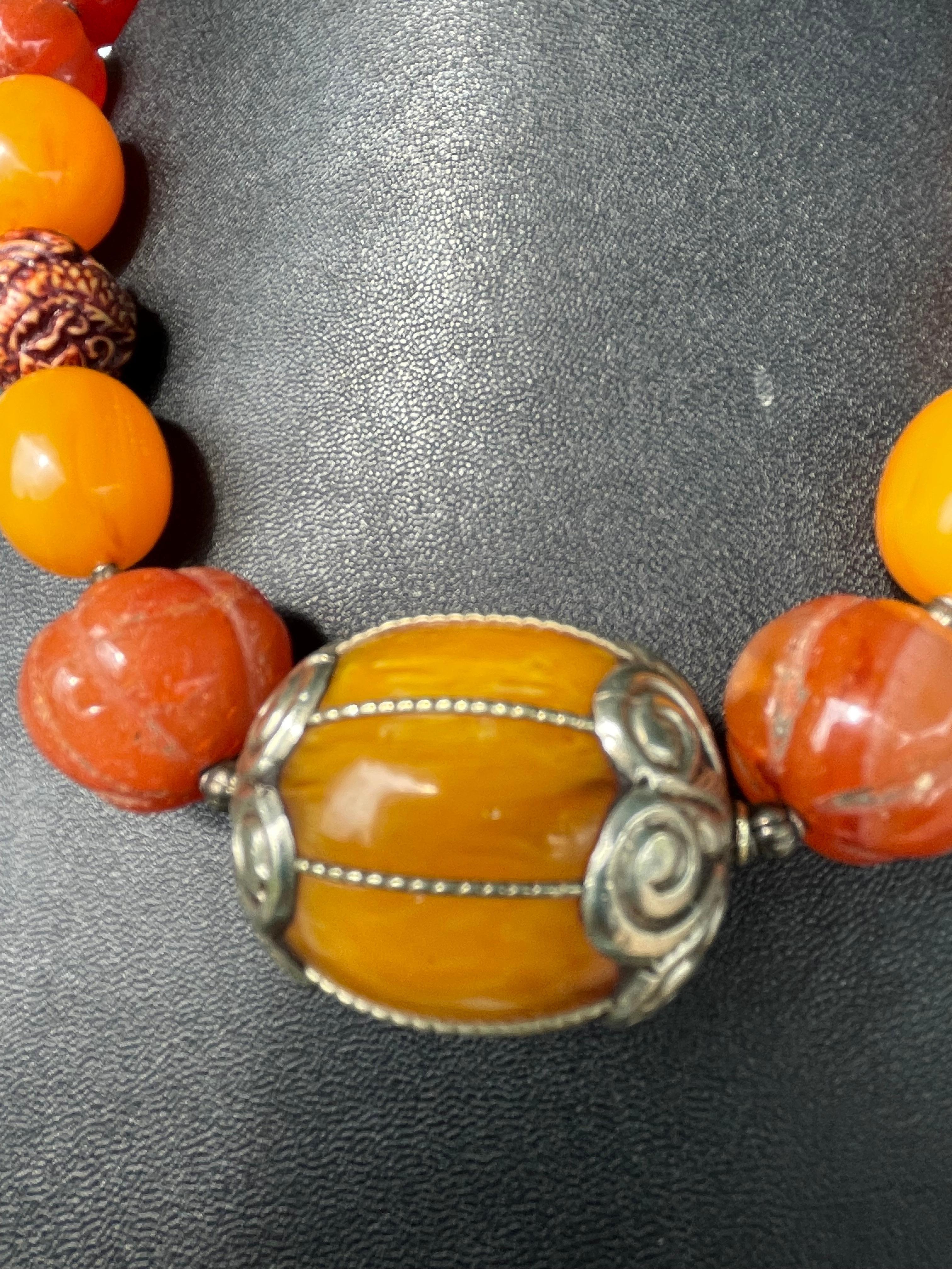 Tribal style vintage Bakelite and Amber beads 
Comprise this handmade, one of a kind necklace.A fabulous center bead of Indian amber with silver end caps is flanked by vintage Tibetan gourd shape carved carnelian beads. A vintage carved nut bead