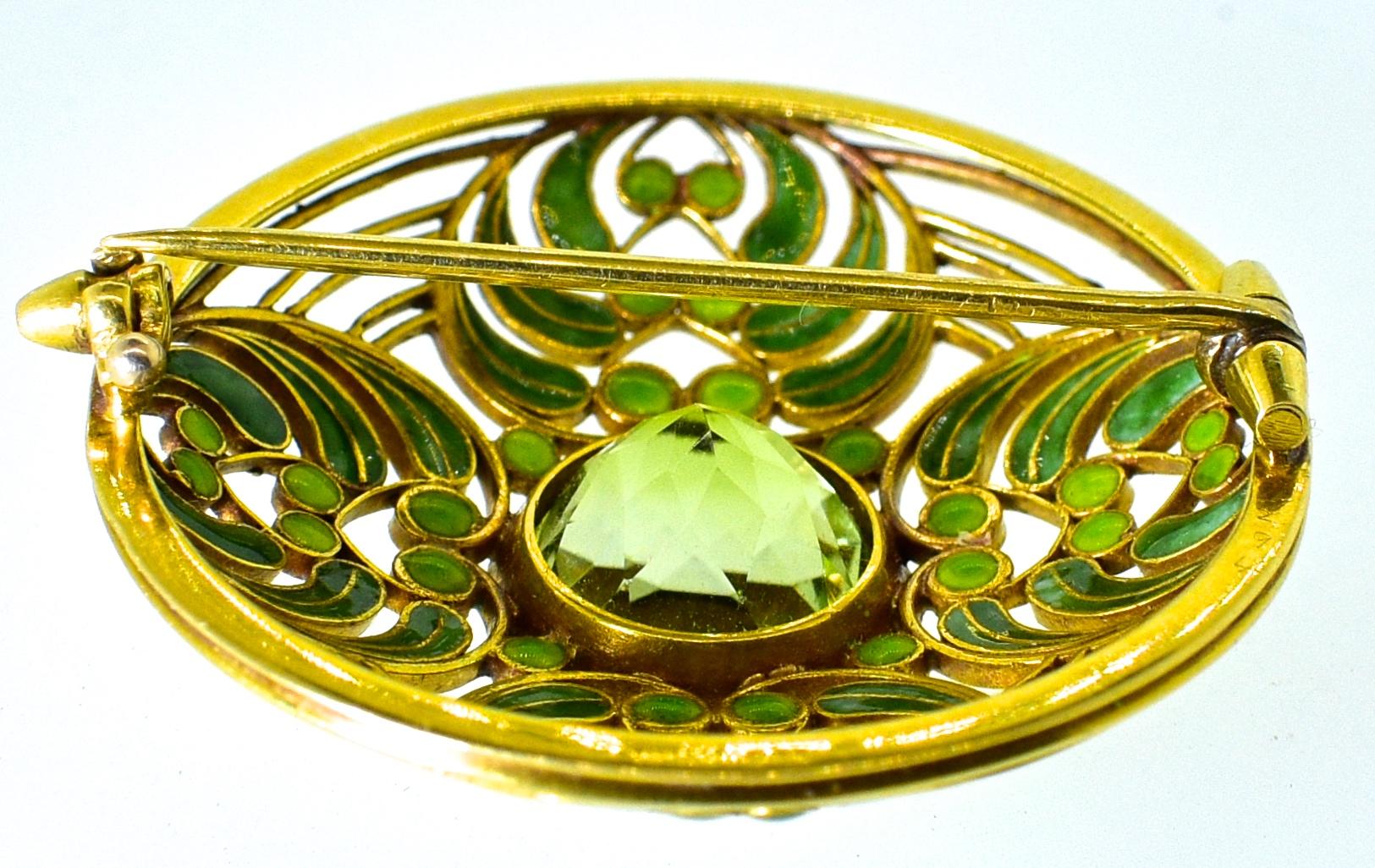 L. C. Tiffany antique brooch decorated with green enamel - on both sides - and centering a round tourmaline (or possibly Demontoid)., weighing over 5 cts.  This 18K brooch signed Tiffany & Co., is unquestionably a masterpiece by Lois Comfort Tiffany