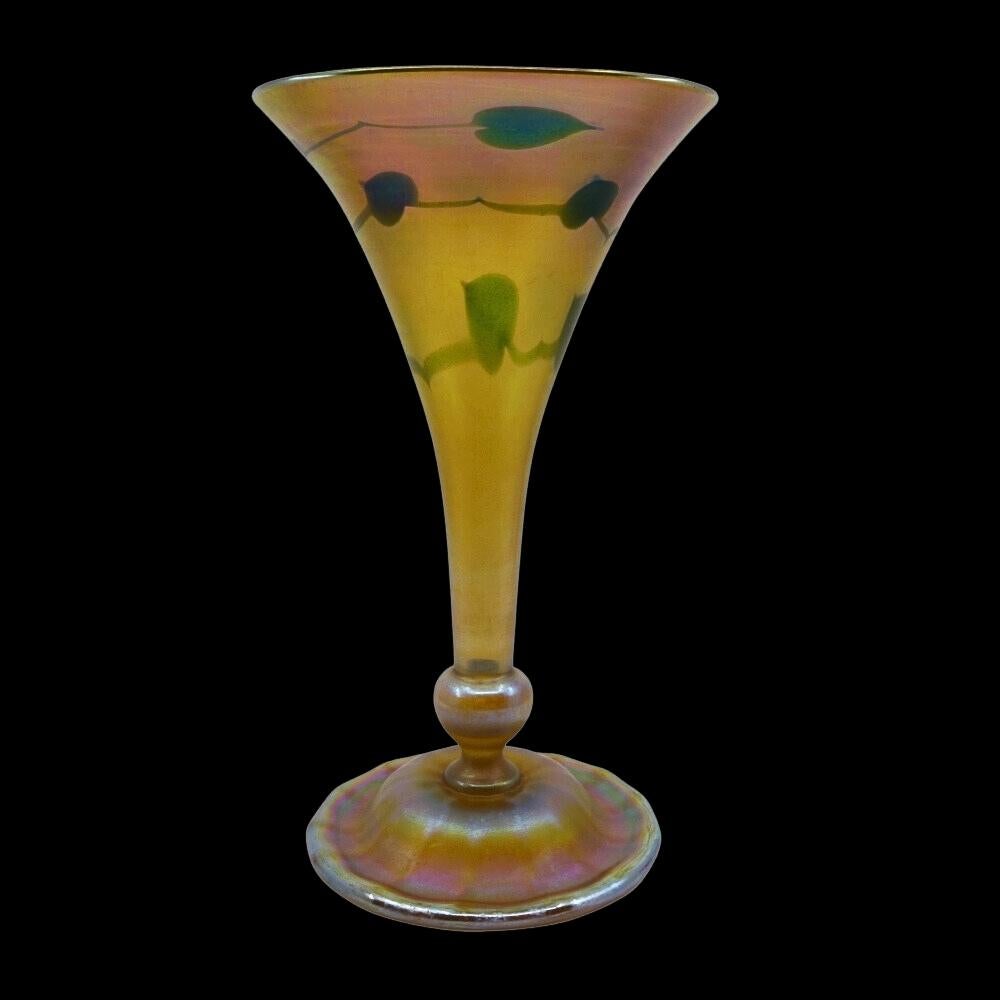 Offering this beautiful, decorated Louis Comfort Tiffany favrile gold art glass vase with green heart and vine decoration. This vase features a fluted, trumpet shaped body with applied, ribbed applied foot. Signed on the underneath 