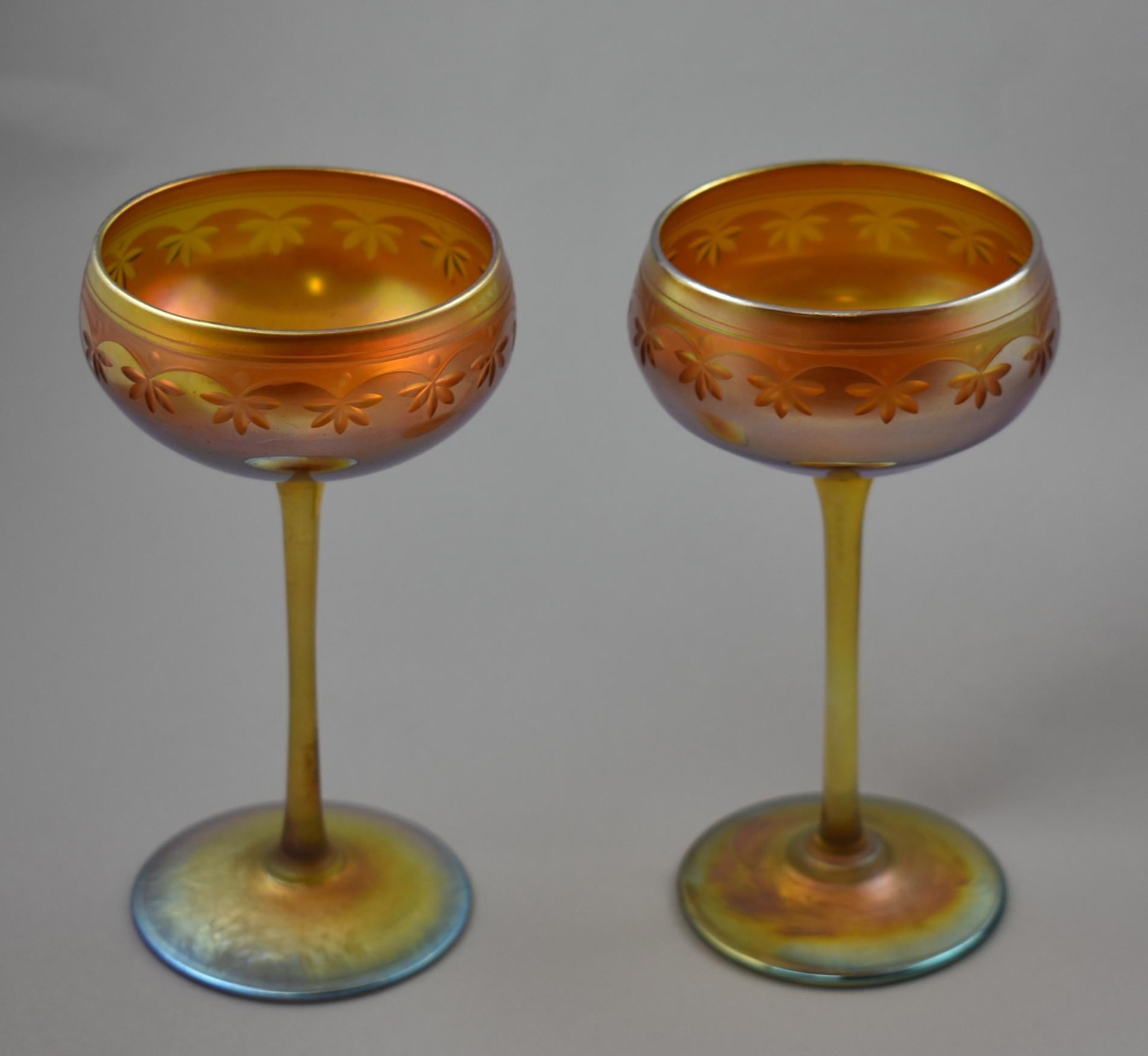 Pair of L.C. Tiffany favrile gold iridescent stemware with wheel cut details. Signed on the bottom. One glass is numbered 233.