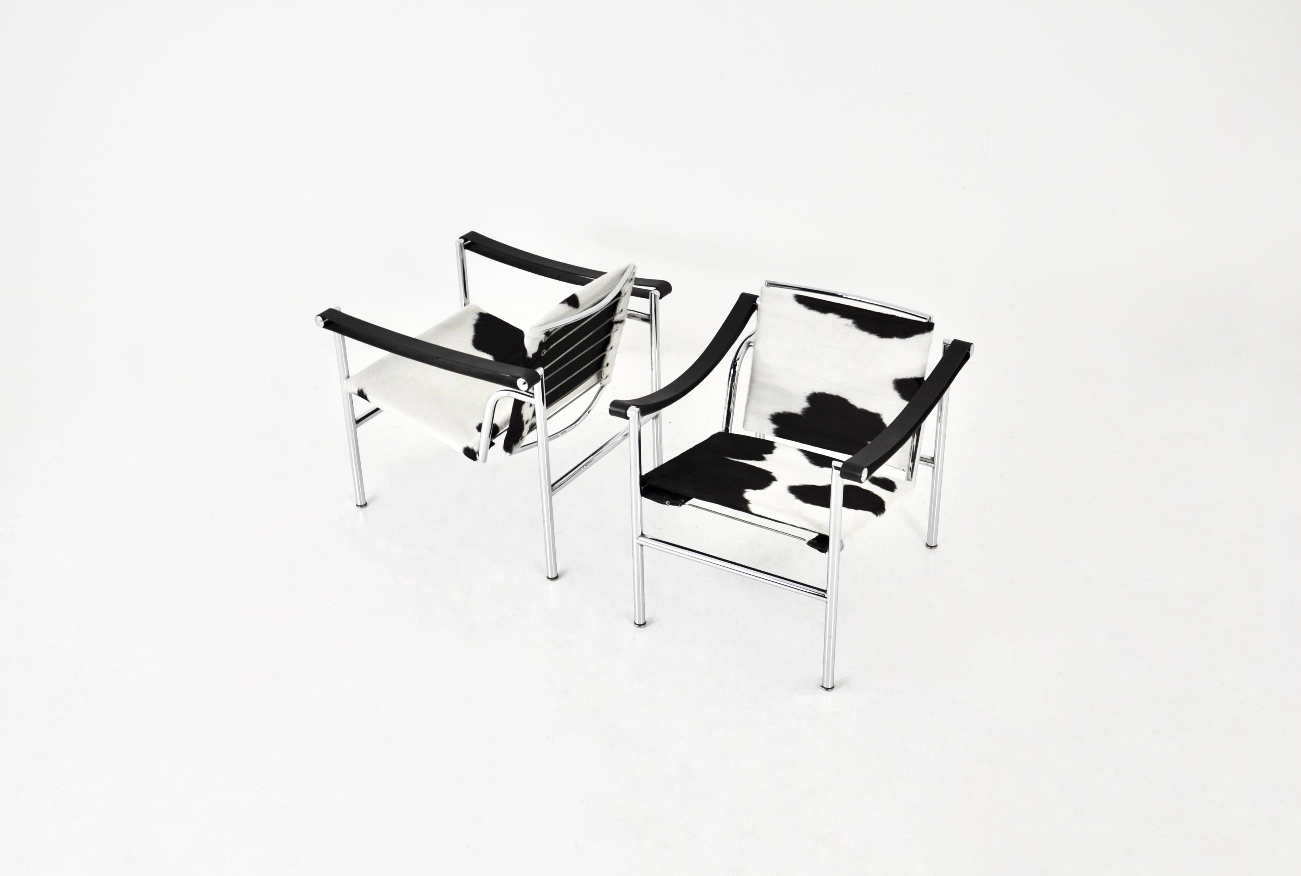 Set of 2 chairs in cowhide and metal frame by Le Corbusier. Stamped Le Corbusier. Seat height: 40 cm. Wear due to time and age of the chairs.