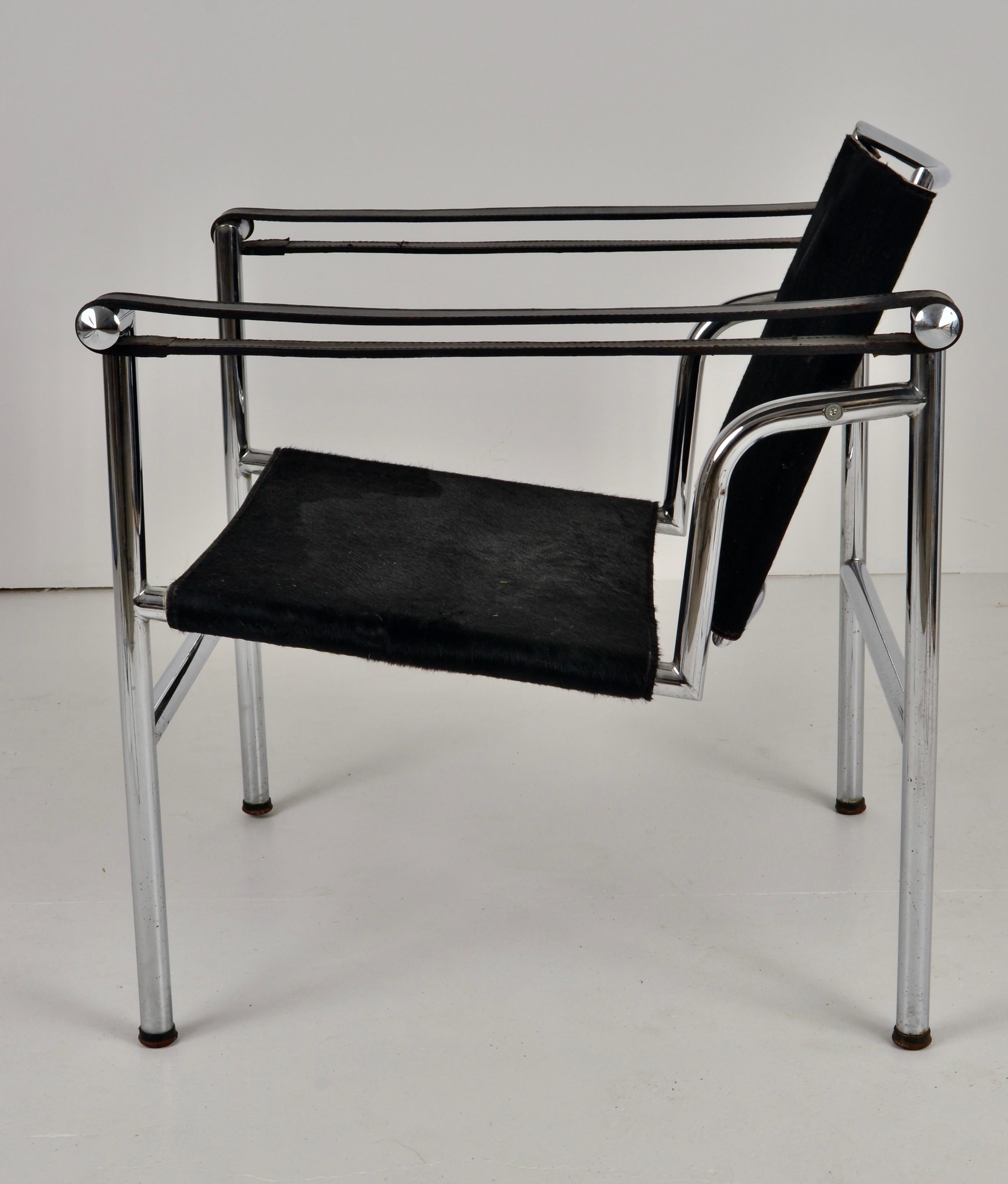 La chaise LC1 est une icône du design moderne, alliant un confort fonctionnel à une esthétique exceptionnelle. Elle est dotée d'une structure en acier tubulaire. Cet exemple présente un départ et un dossier en cuir de vachette poilu noir et des