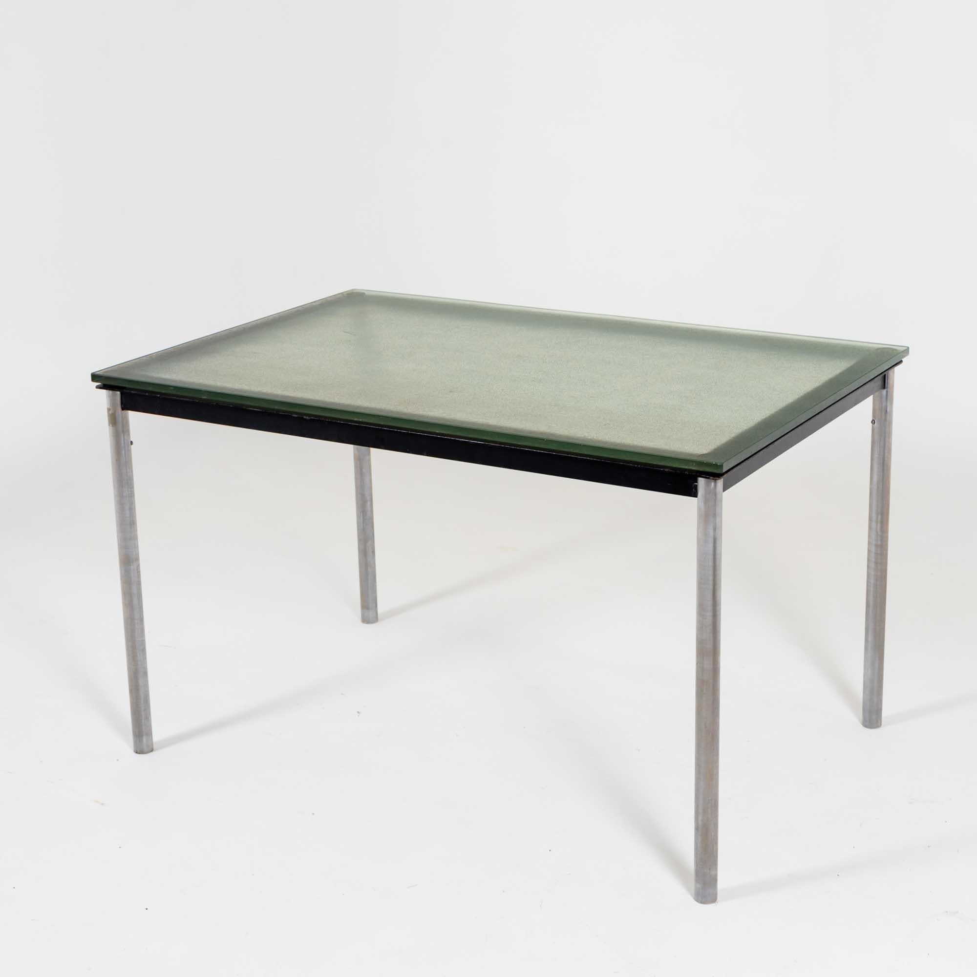 Table ou bureau rectangulaire conçu par Le Corbusier en 1928. Il s'agit d'une édition ultérieure de la société Cassina. La table repose sur des pieds chromés et le plateau en verre teinté vert à la surface légèrement structurée repose sur un cadre