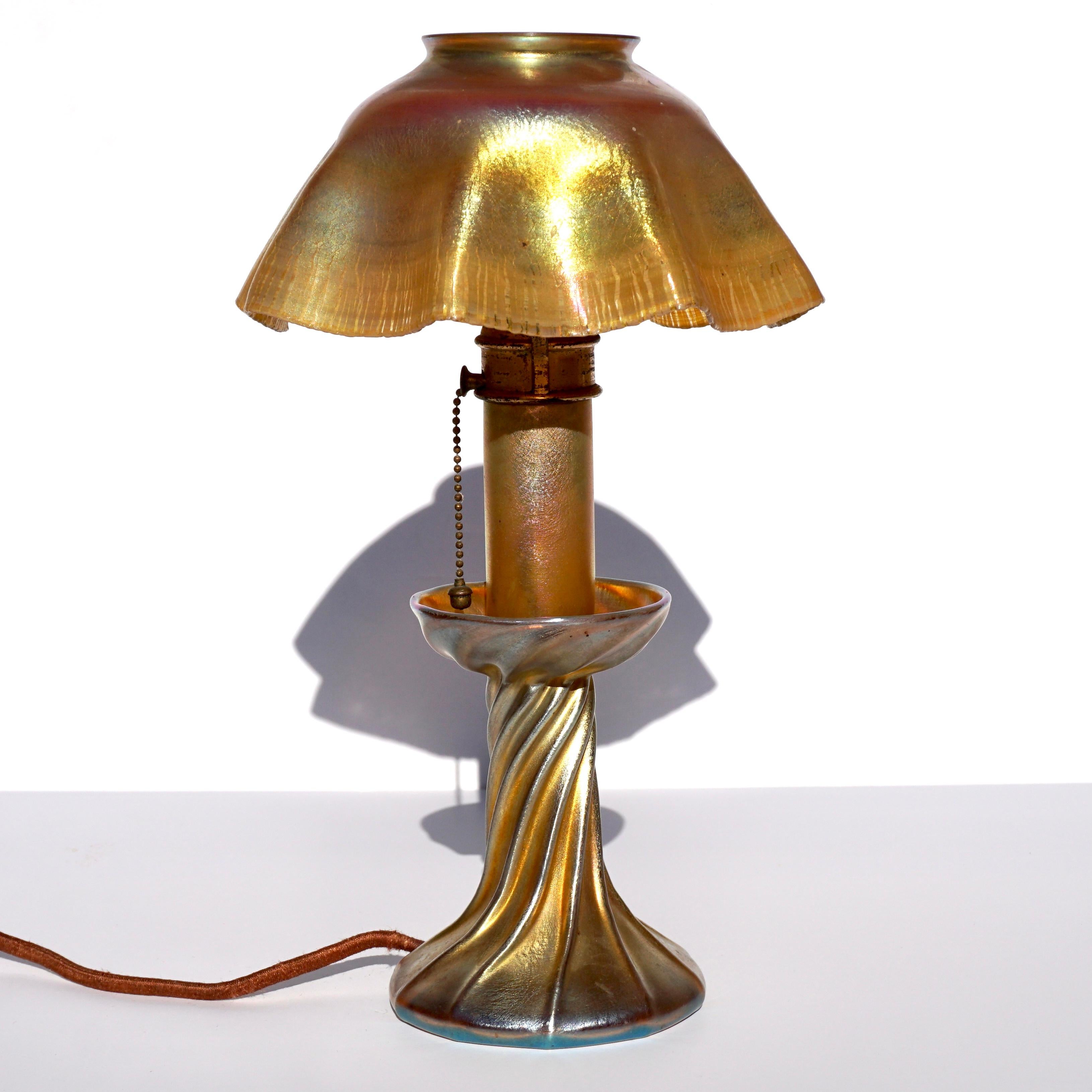 A stunning favrile candle table lamp. Gold. iridescent base, mid section and shade made from Tiffany blown glass with metal harp holding the fluted shade, A perfect gift for yourself or the one you love!

Louis Comfort Tiffany Art Nouveau Favrile