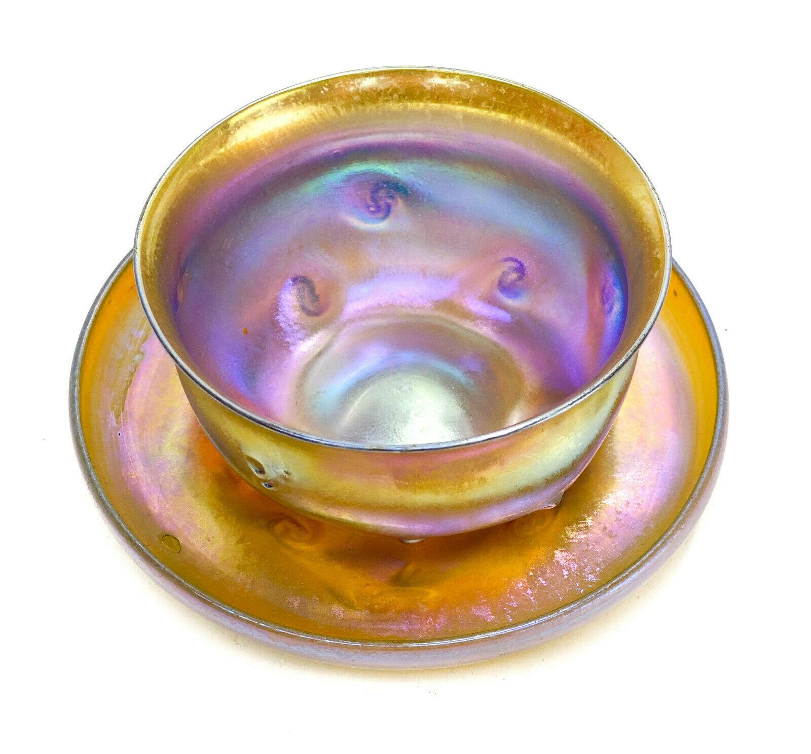 LCT Tiffany favrile gold iridescent bowl and underplate, Prunts, circa 1900.

LCT Tiffany favrile gold iridescent bowl and underplate, circa 1900. Gold iridescence with blue and purple hues. Prunts to the exterior of the bowl and to the underside