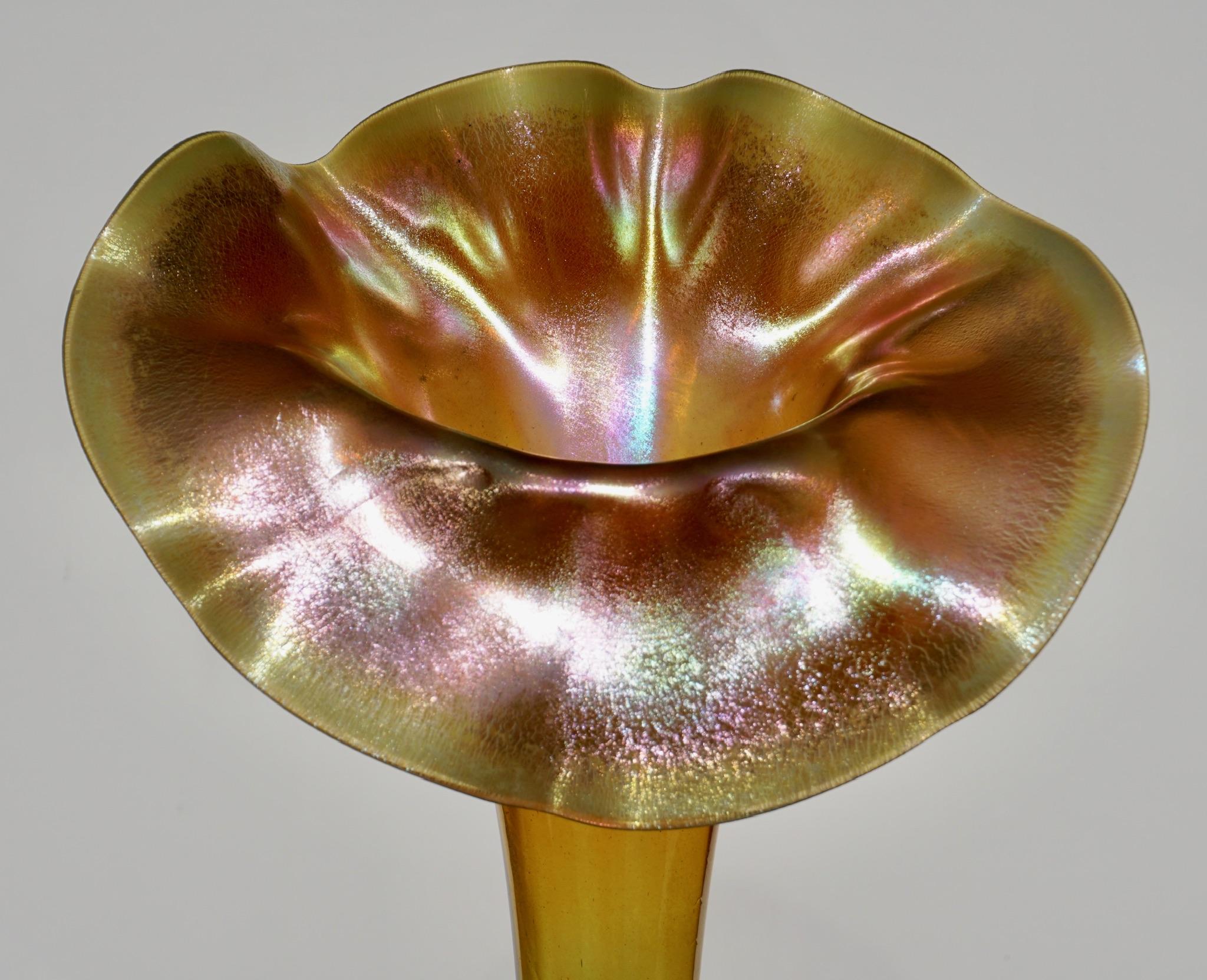 This tall and rare Tiffany Studios jack in the pulpit vase has an inverted saucer foot with opalescent wafer transition stem to foot. The transparent green glass stem leads to the bowl which fades from green transparent to gold iridescent. The face