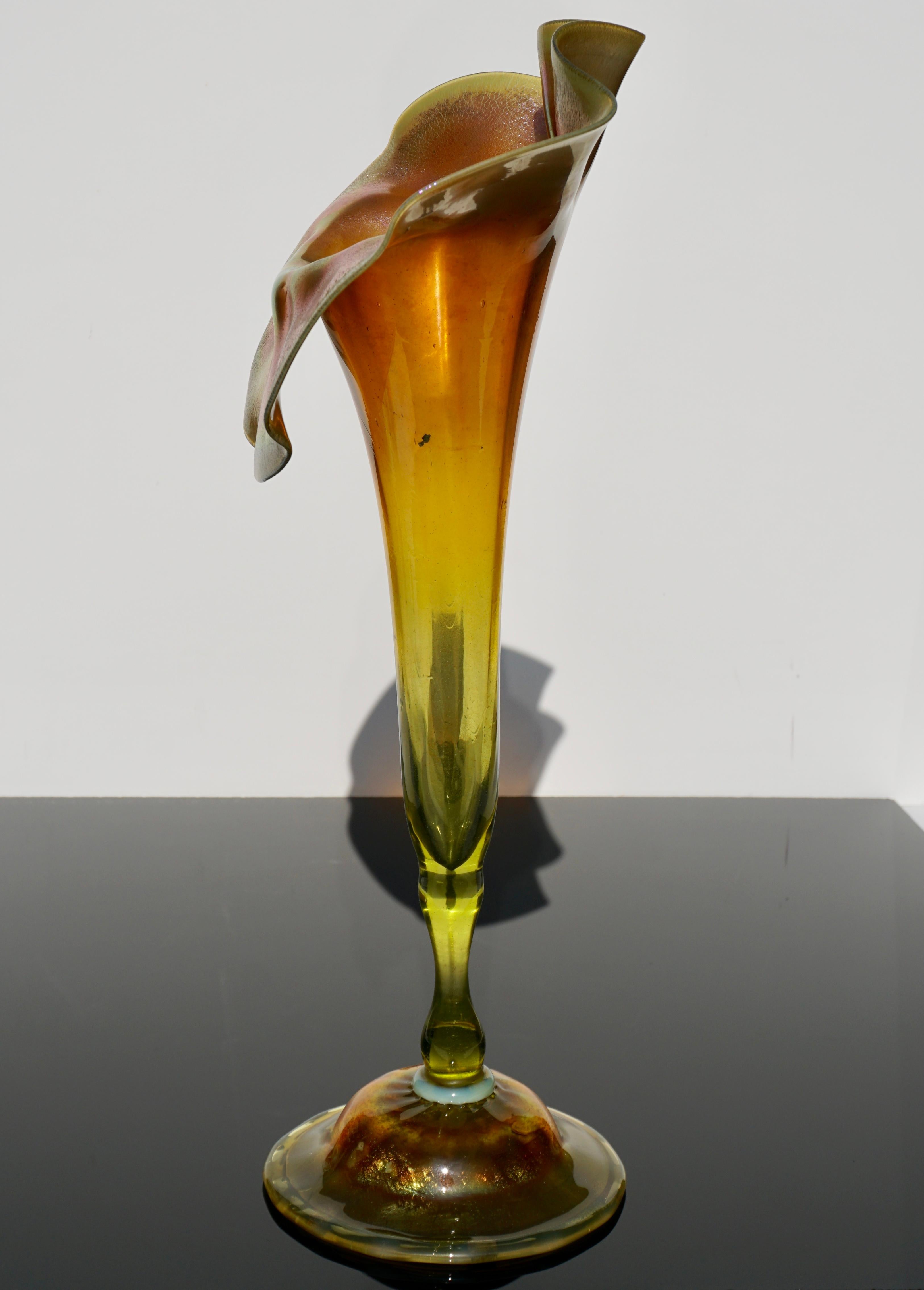 This tall and rare Tiffany Studios vase has an inverted saucer foot with opalescent wafer transition stem to foot. The transparent green glass stem leads to the bowl which fades from green transparent to gold iridescent. The face of the jack has