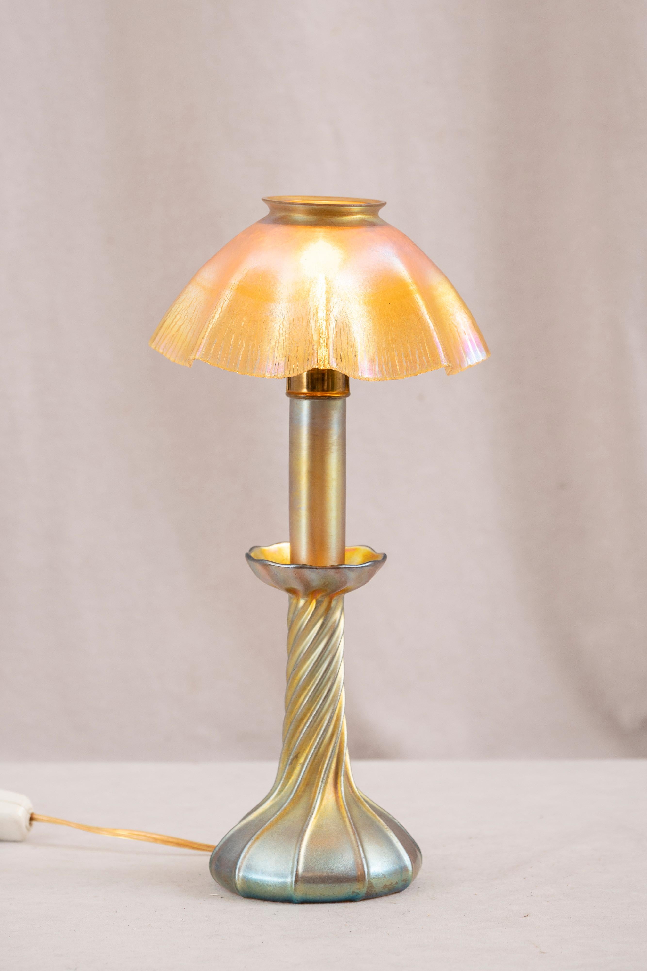  Questa bella e graziosa lampada Tiffany è stata creata dal più rispettato creatore di lampade, Louis Comfort Tiffany. La base e il paralume sono entrambi originali in vetro soffiato a mano e portano la firma di A.L.C.. Il vetro color oro ha un