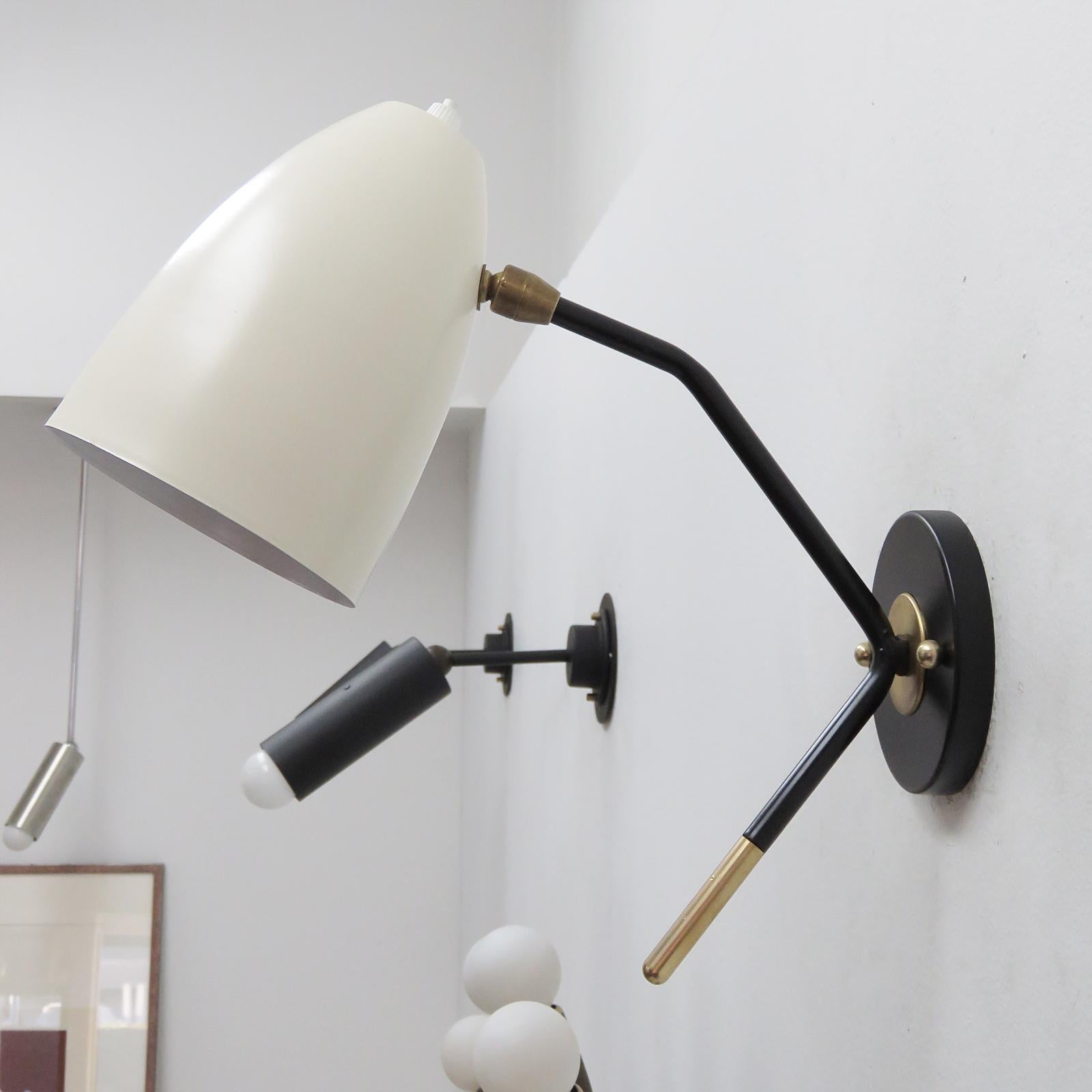 Wonderful LE-1 wall lights with fully adjustable two tone brass shades (egg shell with white enameled interiors) on black enameled arms with decorative brass tips, each shade has an individual on and off switch. One E26 socket per fixture, max.