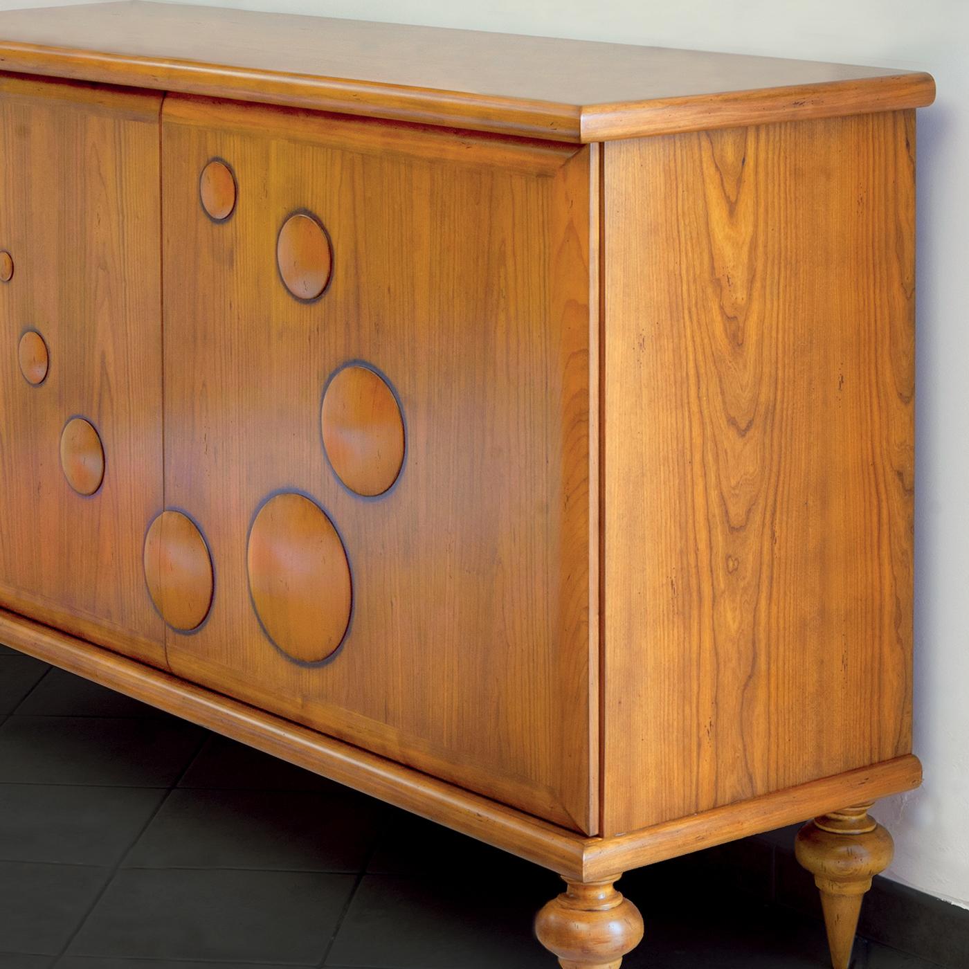 Part of Le Bolle collection marked by carved bubbles turning the solid cherrywood structure into a vibrating and dynamic design, this handsome sideboard will be a statement piece in a rustic-chic interior decor. Raised on four uniquely shaped legs,