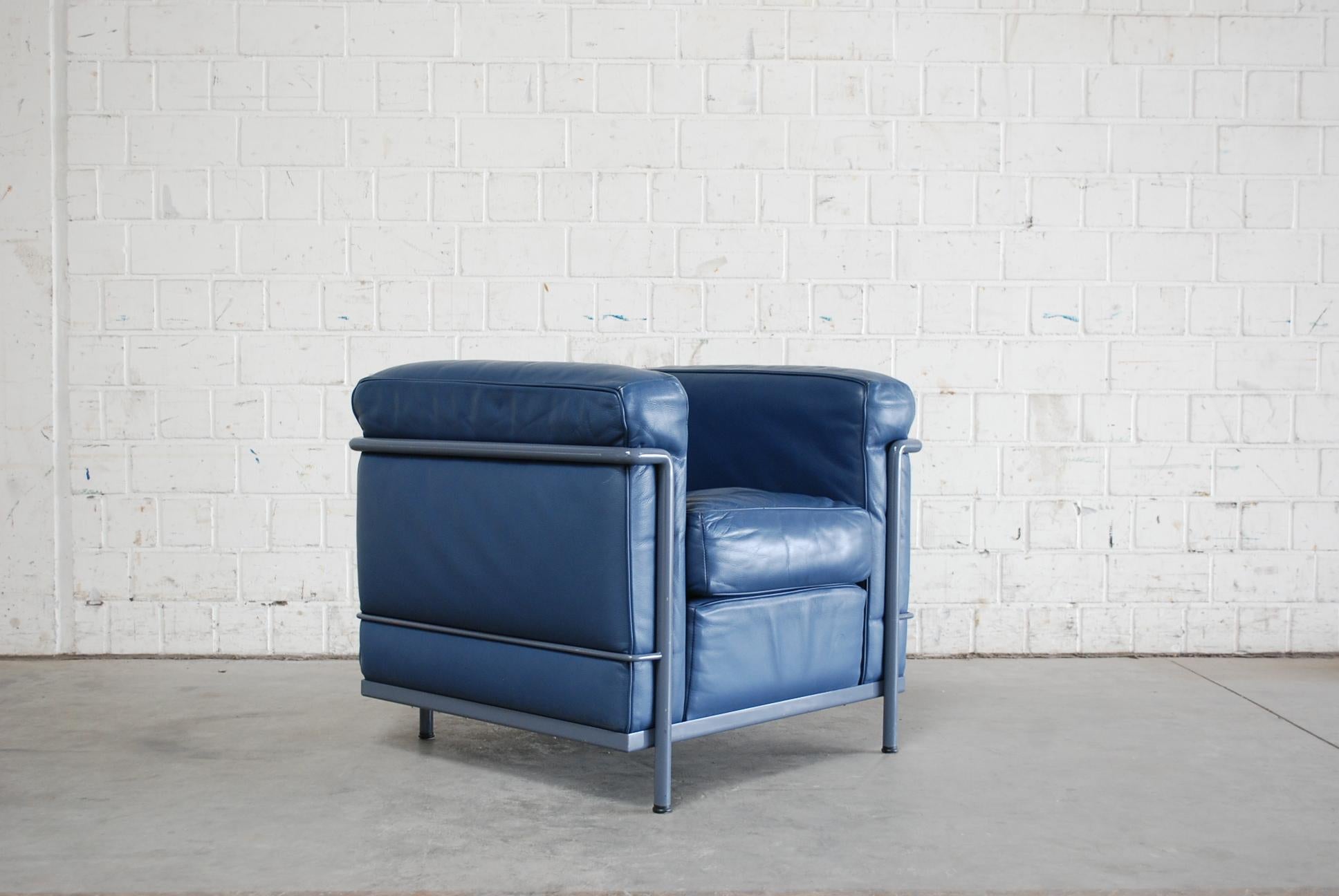 This LC2 armchair in blue leather was designed by Le Corbusier/ Pierre Jeanneret/ Charlotte Perriand and produced by Cassina. 
It features a blue/ grey colored tubular steel frame. Some marks on the tubular frame.