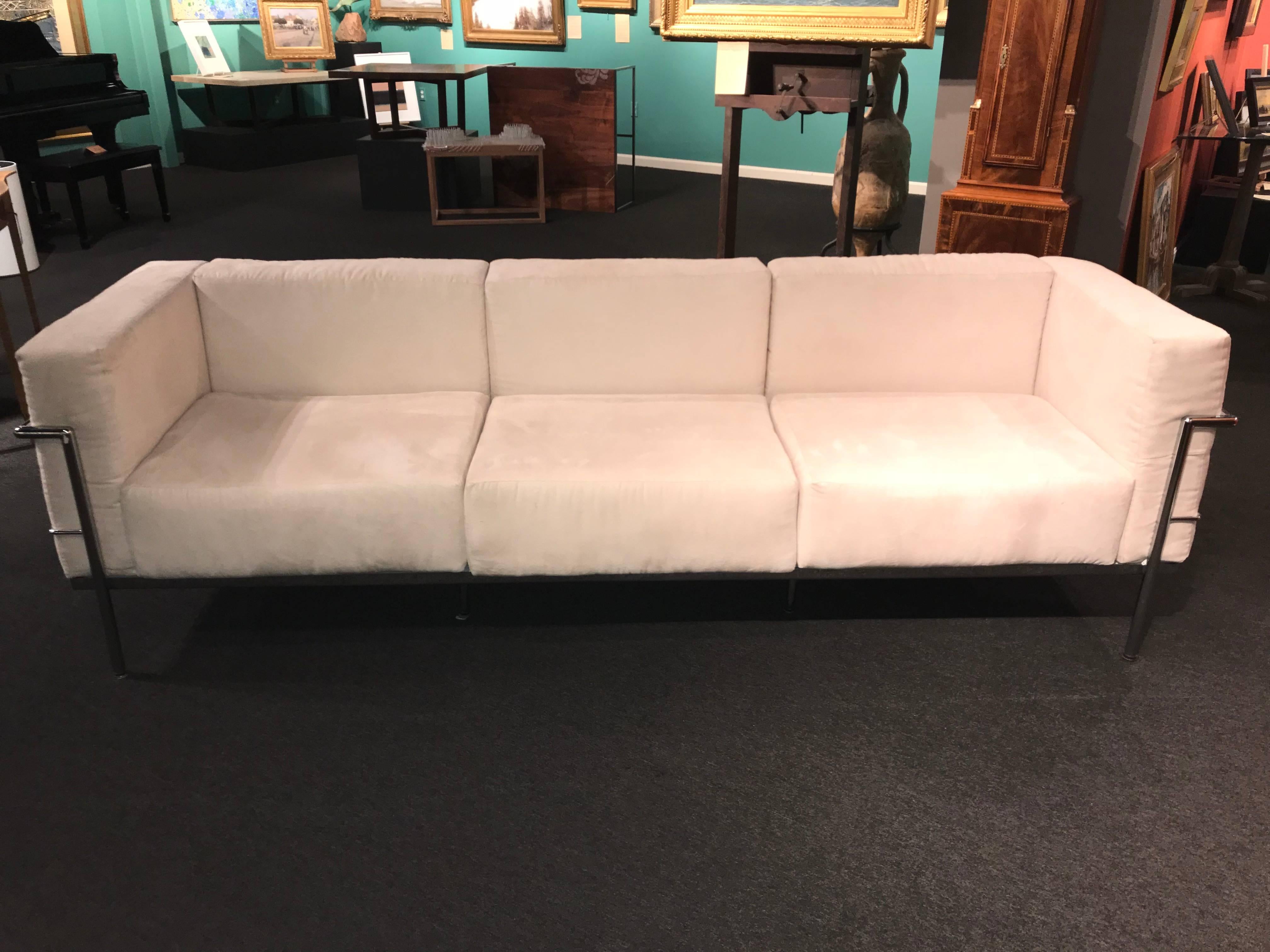A fine modern triple-seat sofa in cream or off-white suede on an eight-leg highly polished chrome stainless steel frame, with woven canvas seat support and a lined under support panel. Swiss designer / architect Le Corbusier (Charles-Édouard