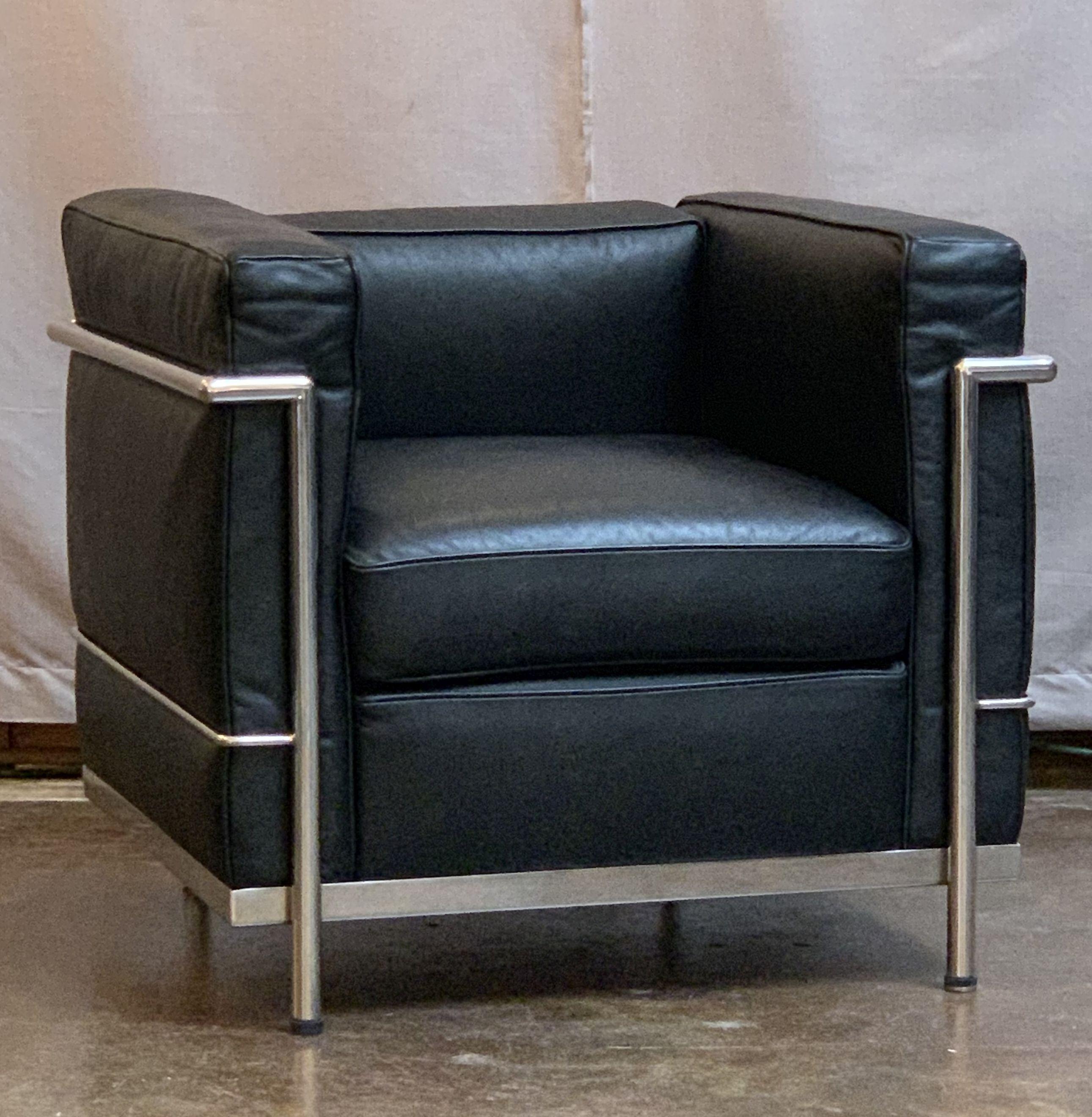 A pair of vintage black leather chairs, each featuring the stylish chrome frame and black leather upholstered cushions made famous by Le Corbusier, Pierre Jeanneret and Charlotte Perriand in their work for Cassina. Each chair offers comfortable