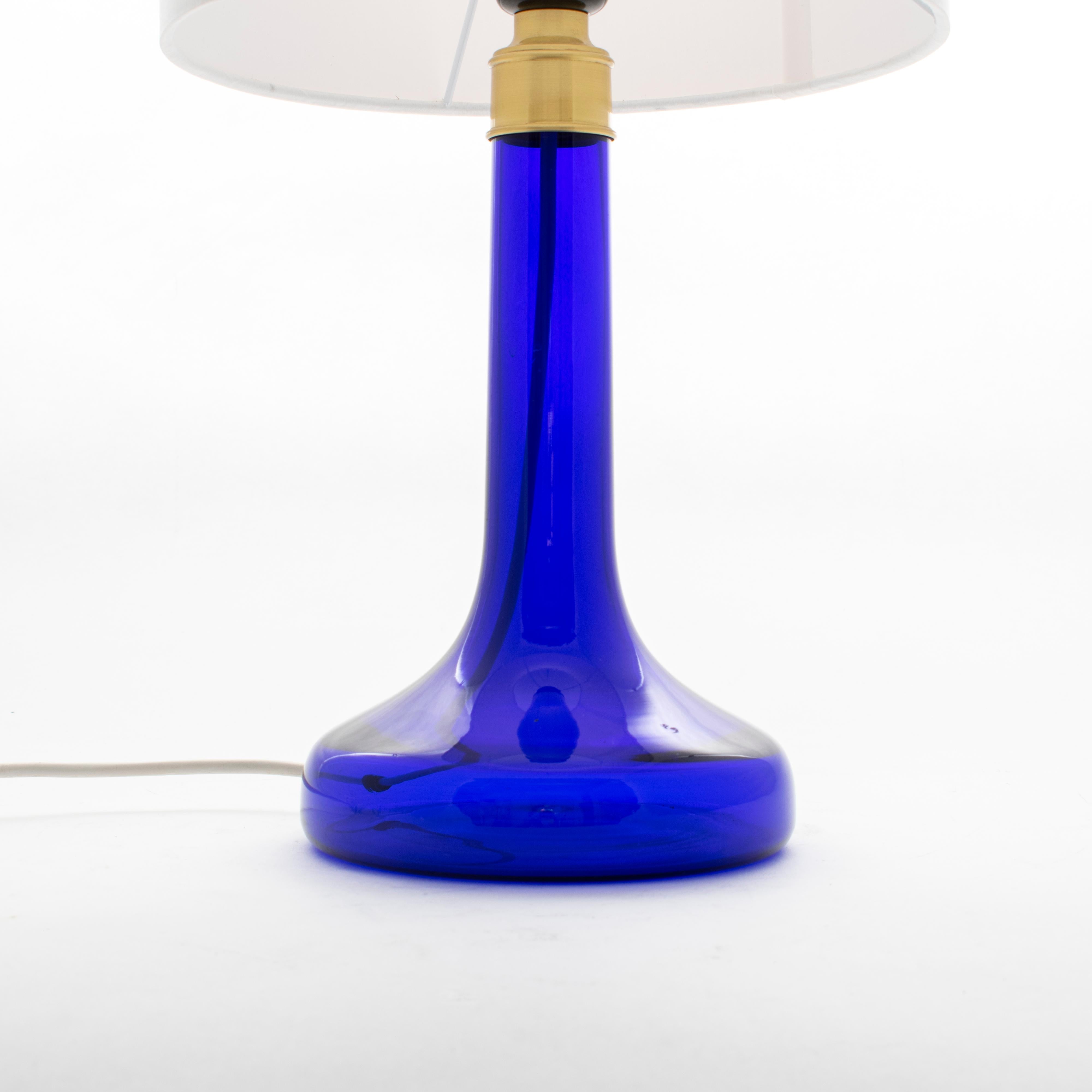 Danish table lamp model 343 by designer by Biilmann-Petersen.
The lamp foot is made of mouth blown translucent dark blue glass from Holmegaard glass works and has a top made of brass.

Measures: Height lamp base without socket: 26 cm
Height lamp
