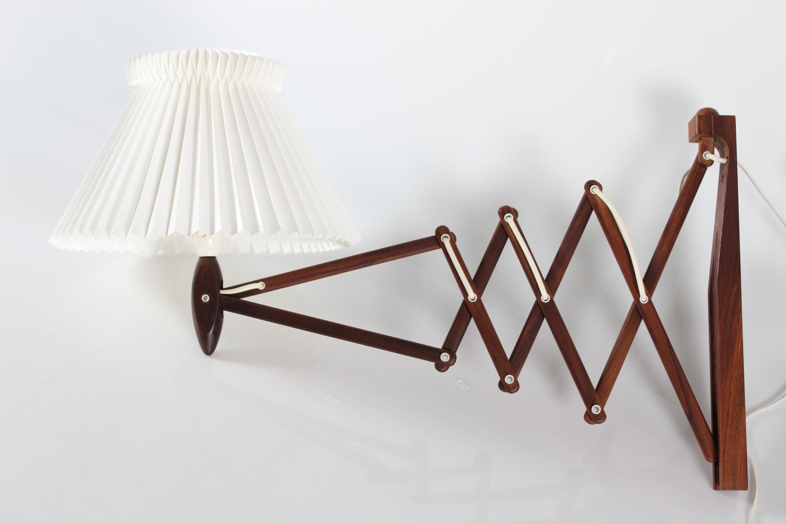 Vintage Le Klint wall lamp model 234 by Erik Hansen.
It's made of solid rosewood with a factory new original Le Klint lamp shade of white plastic designed by Tage Klint.
It is possible to adjust the length of the lamp

Measures: 
Length or depth