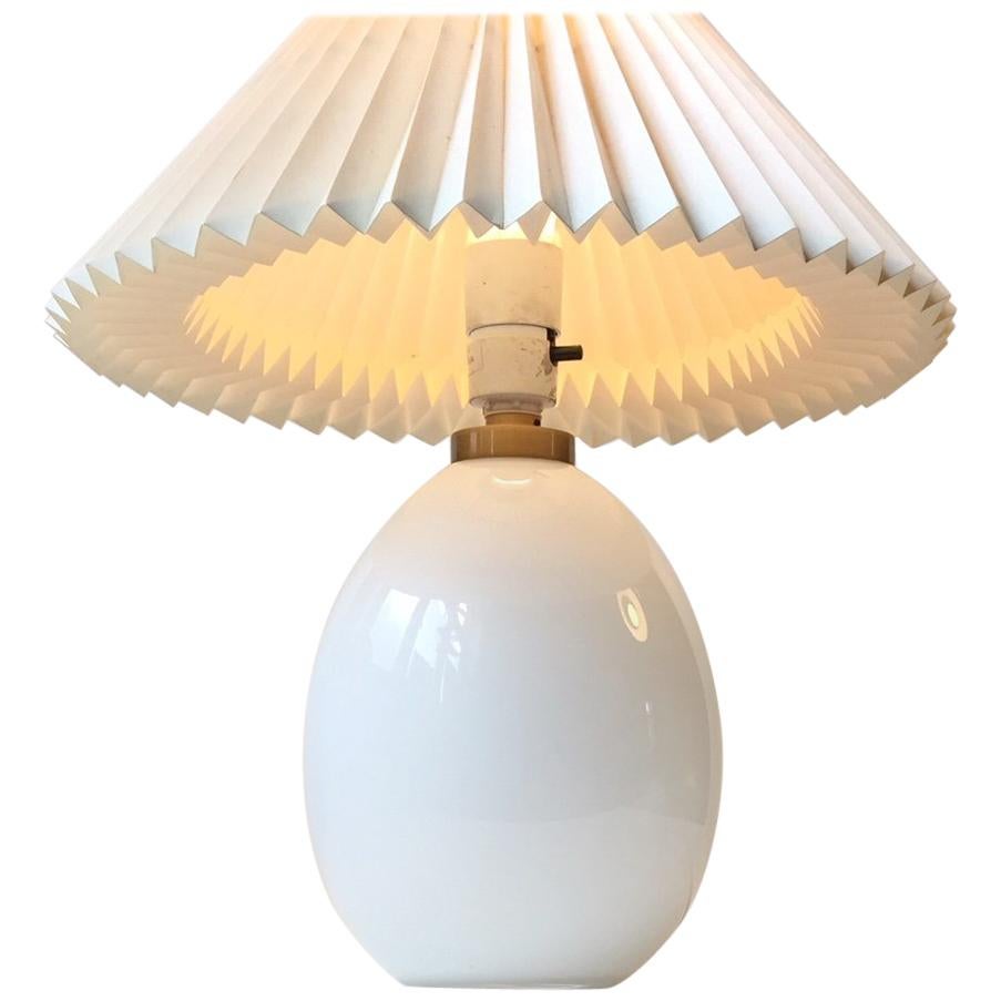 This egg-shaped white opaline glass table lamp was designed by Poul Seest Andersen and manufactured by Le Klint in Denmark during the late 1970s or early 1980s. It features a pin-on/off switch, a brass top and the maker's mark to the base. Please