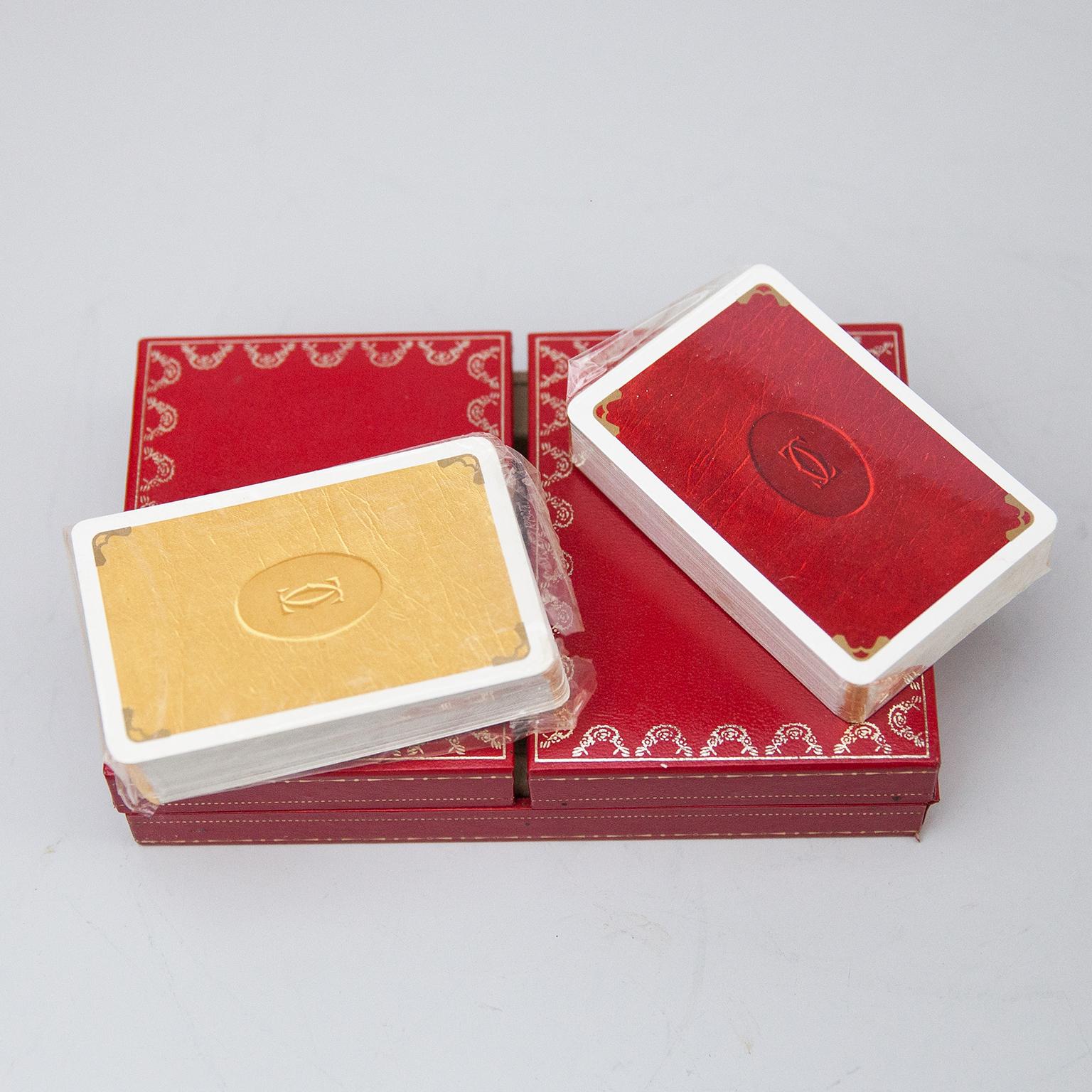Never in use Cartier playing cards box, one deck plus joker, poker, bridge playing cards in Cartier red 2-doors case. Les Must de Cartier playing cards were only sold from 1972-1976. The silk-lined box of cards with 18-karat gilded corners, printed