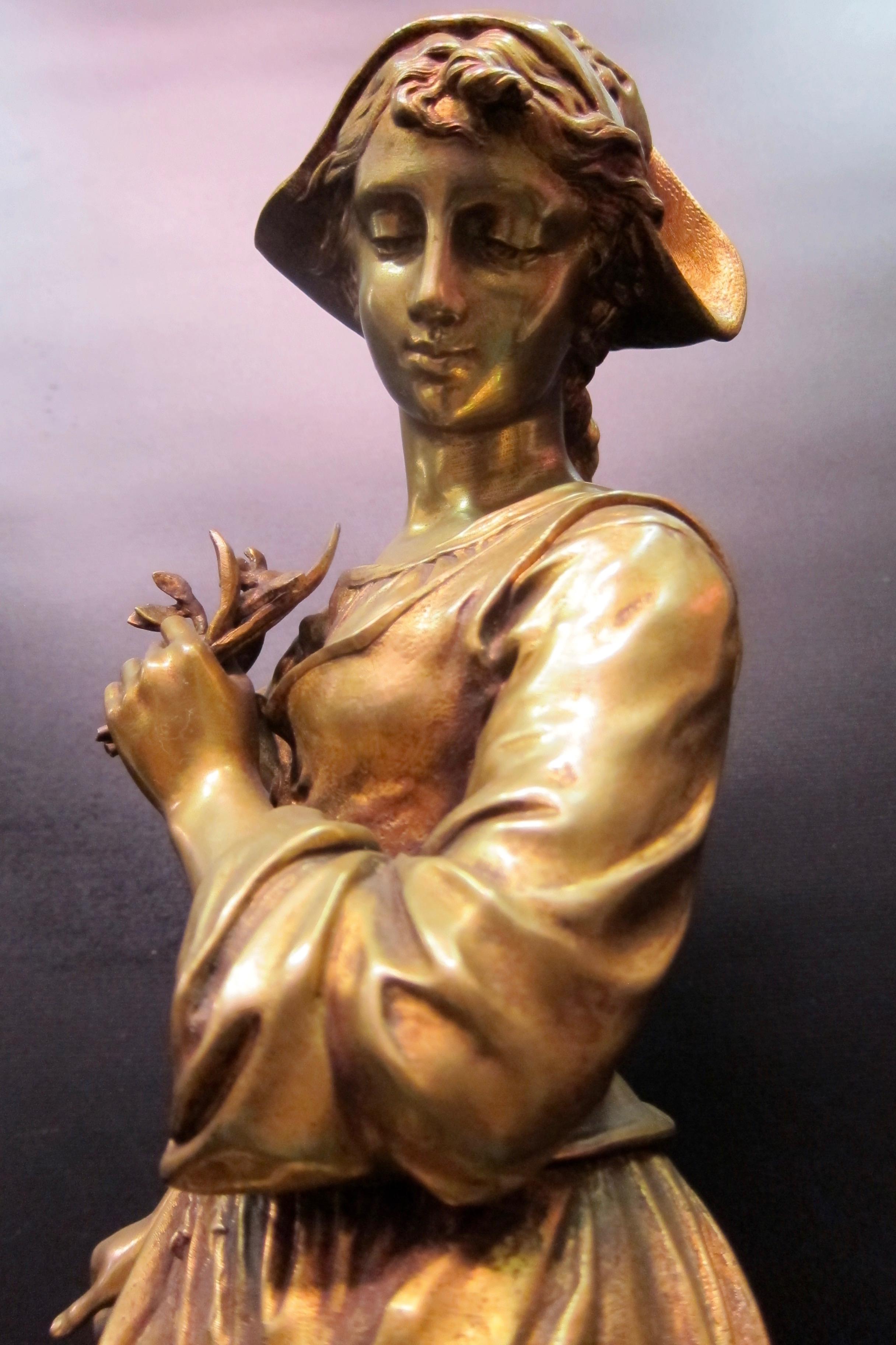 This vintage bronze sculpture off a young French maiden costumed in a flowing garment is signed by the artist, E. Tassel. She is exceptionally well detailed from head to toe. The subject casts her eyes downward as she carefully balances herself