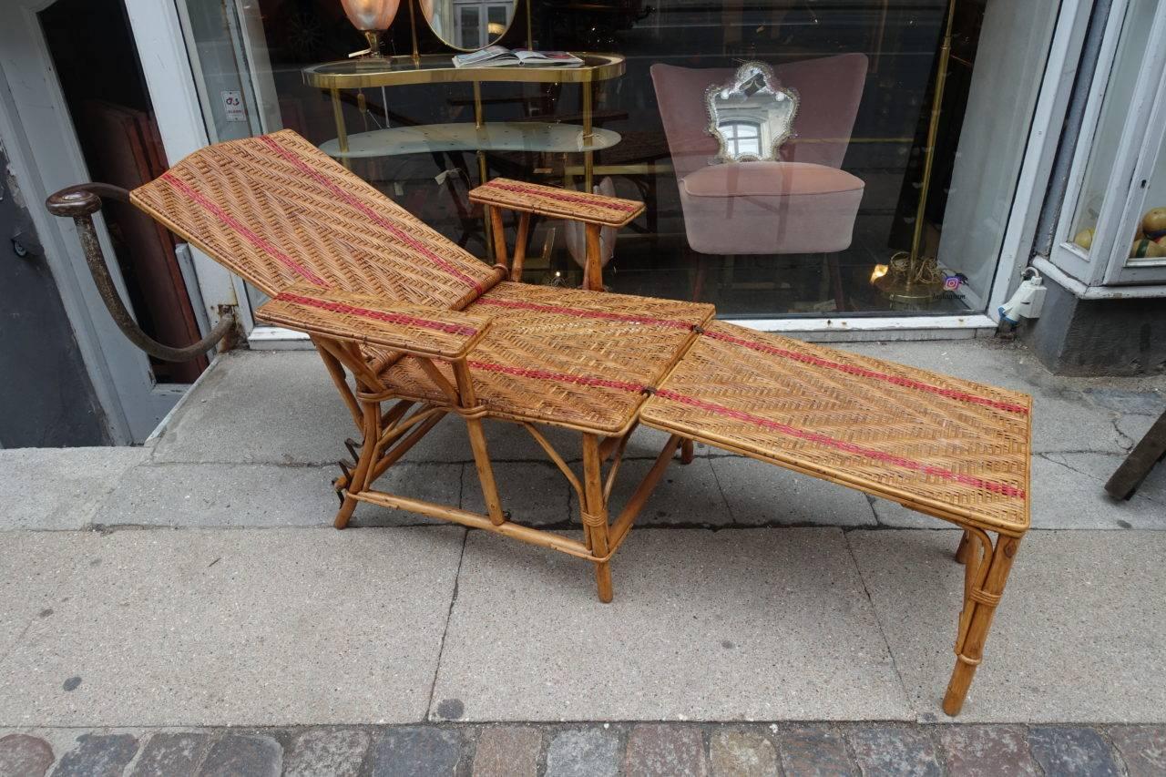 Gorgeous vintage French two-part sun lounger, of bistro chair style rattan wicker, with its red stripes interwoven. Ideal for a pavillion, balcony or covered terrace. Adjustable back, comfortable arms, and removable foot stool. Wonderful patina.