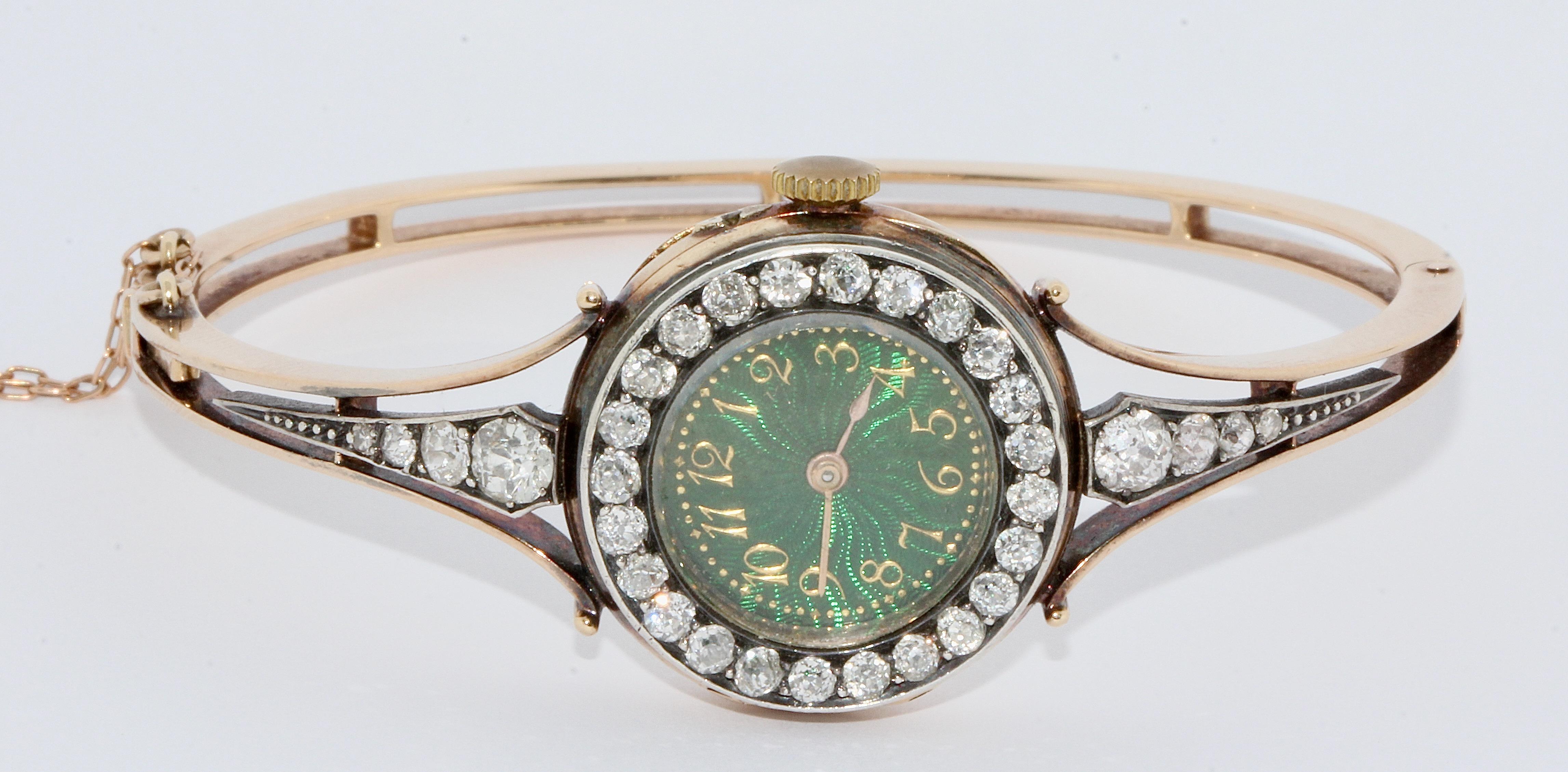 Prächtige, antike Damenarmbanduhr aus Gold mit Diamanten und Emaille-Zifferblatt.


Die Uhr ist mit insgesamt 32 Diamanten im Altschliff besetzt.
Auffällig ist das schöne, grüne Emailzifferblatt mit goldenen arabischen Ziffern.

Armreif und Etui
