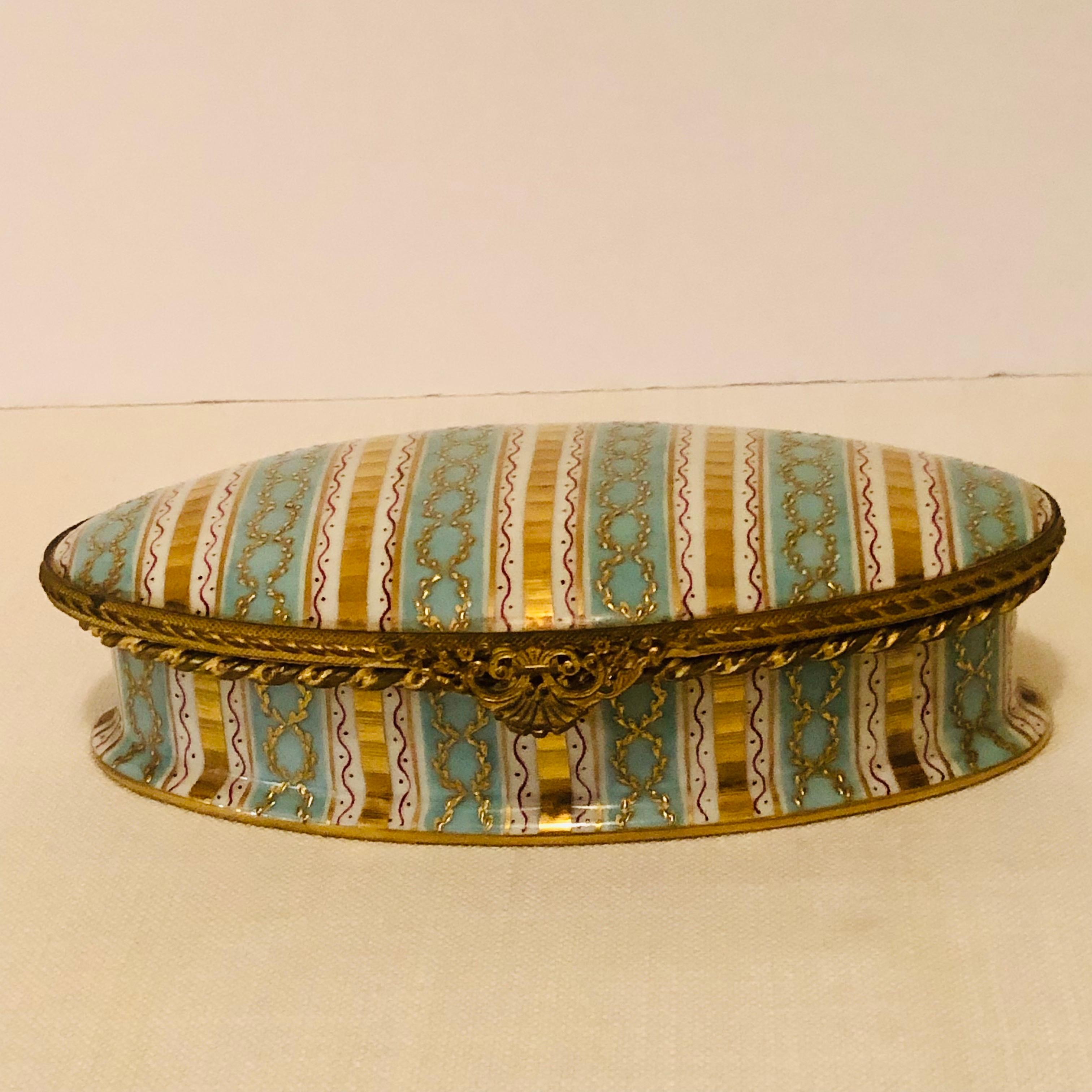 This is a beautiful Le Tallec box with aqua and gold stripes on a white ground. It has a decoration of raised gilding in the form of circular chains on the aqua stripes. The ormolu around the box top and bottom is an intricate gold design, as you