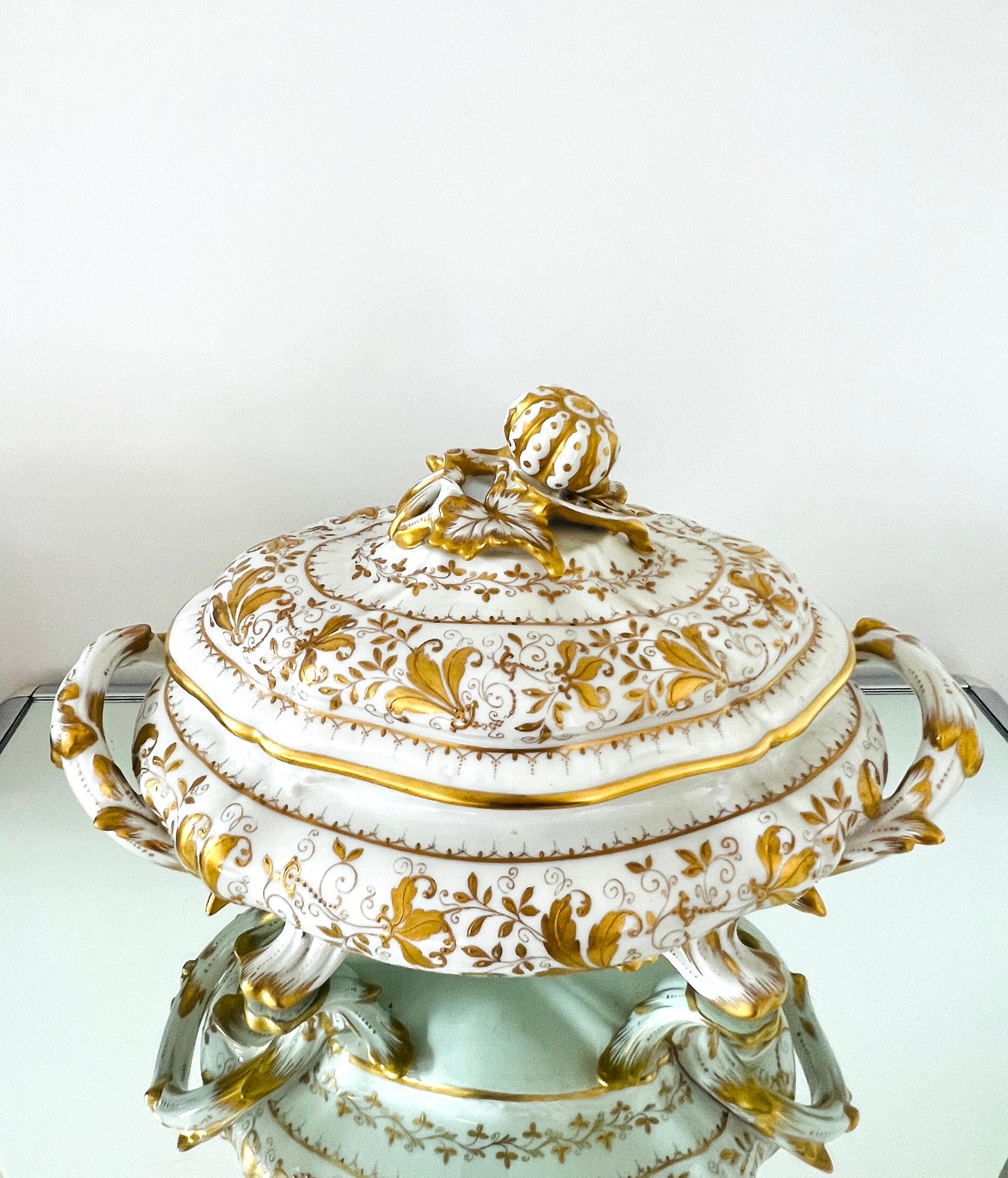 Exquisite hand-painted porcelain soup tureen by Camille Le Tallec. Inspired by designs of the Rococo Era, the lidded tureen has stylized feet and double handles featuring painted acanthus and foliage motifs in 24K gold leaf. The embellished lid is