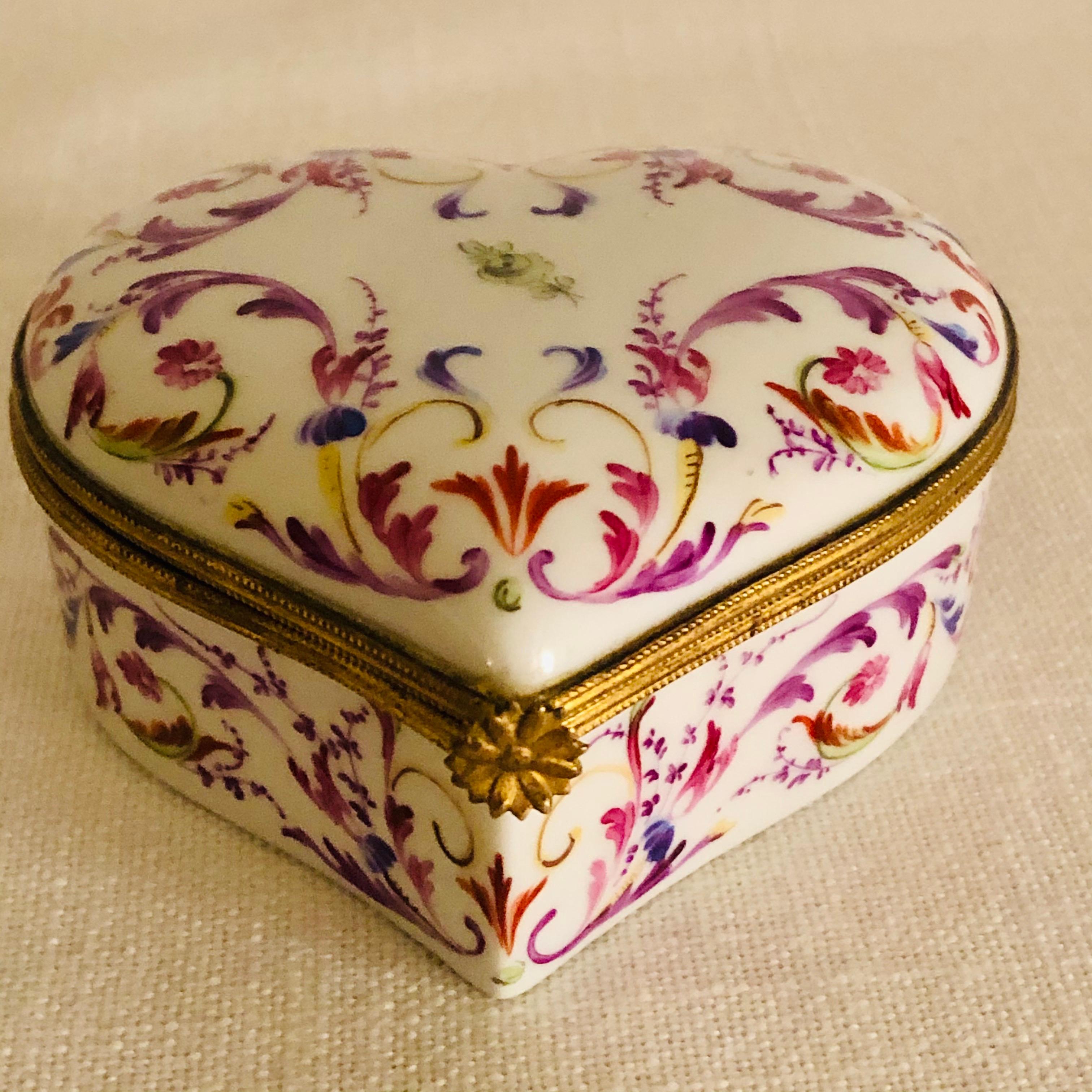 I want to offer you this charming Le Tallec porcelain heart shaped box. It is painted with flowers and an arabesque colorful decoration. The colors of this box are so eye catching with its purple, pink, green and orange intricate painted design. It
