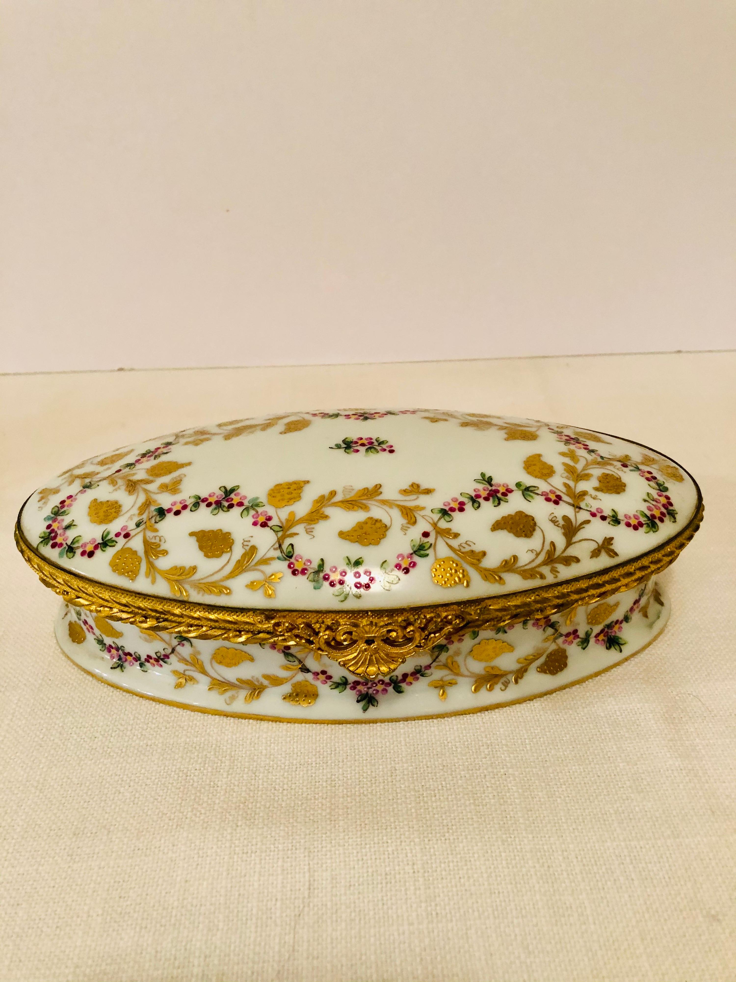 This is a beautiful Le Tallec oval box. It has raised gilding of leaves and raspberries, and a raised enamel ribbon decoration of flowers. Scroll through the pictures to see the exquisite artwork on this Le Tallec box. You can see that the hinge of