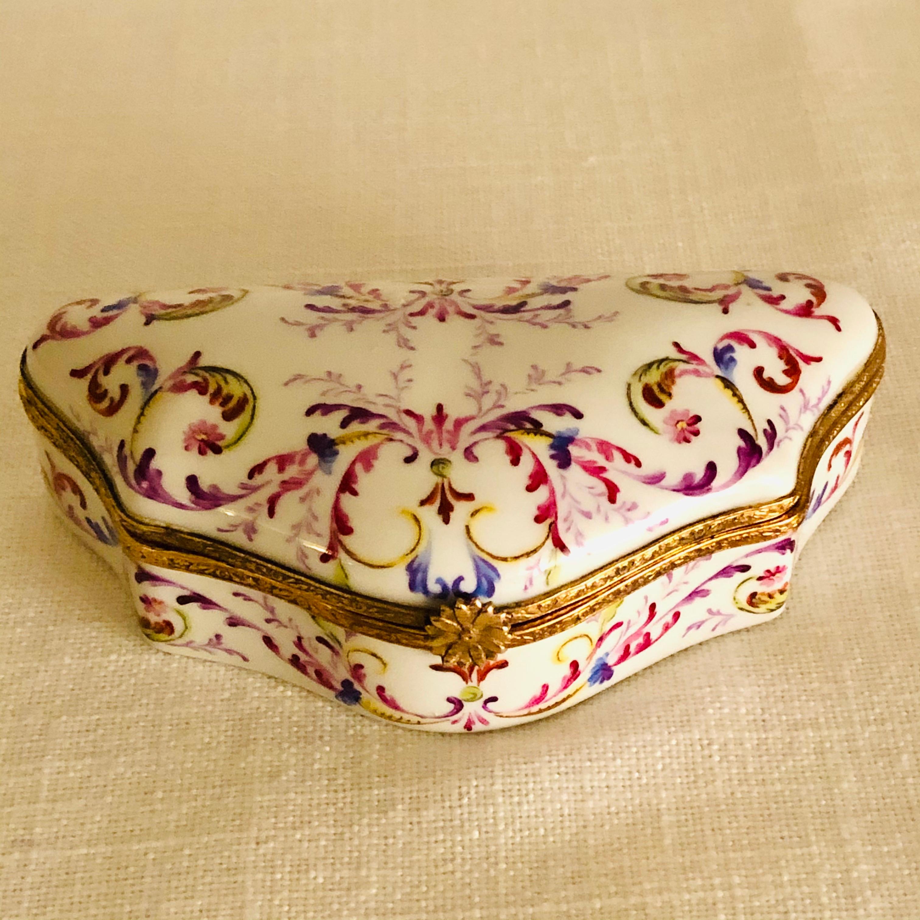 This is a stunning Le Tallec porcelain box. It was designed at the studio of Le Tallec in Paris, which was at a later date incorporated into Tiffany and Company. It is decorated with an elaborate scrolling design of many colors and flowers. The eye
